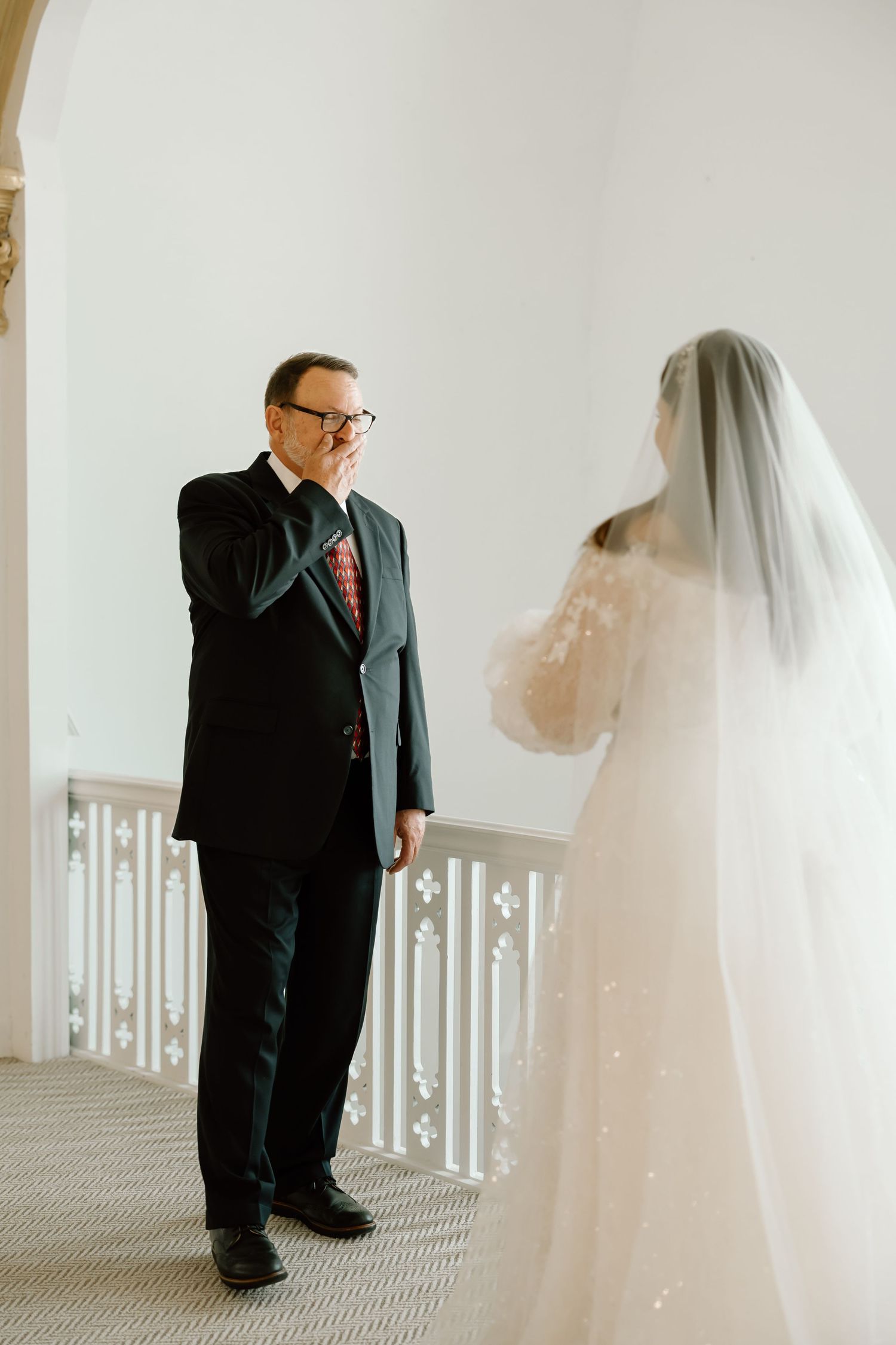 Emotional father seeing bride daughter in wedding dress and veil for the first time on wedding day.