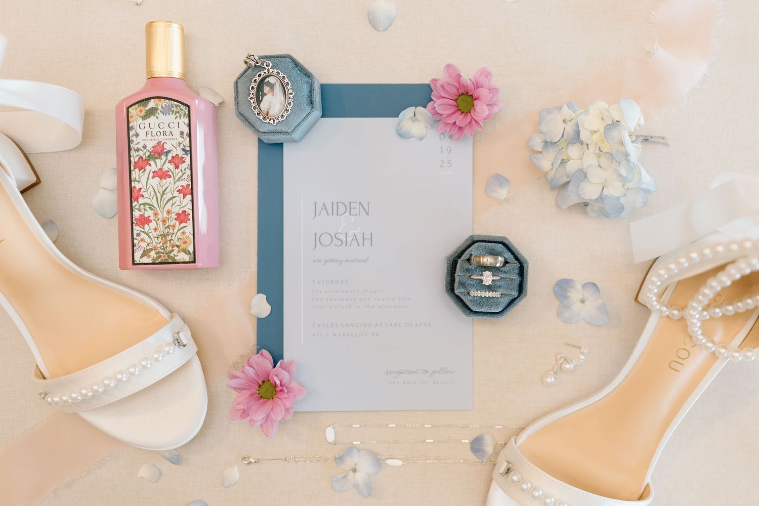 Flatlay of wedding details including shoes, invitation and pink flowers on a peach background.