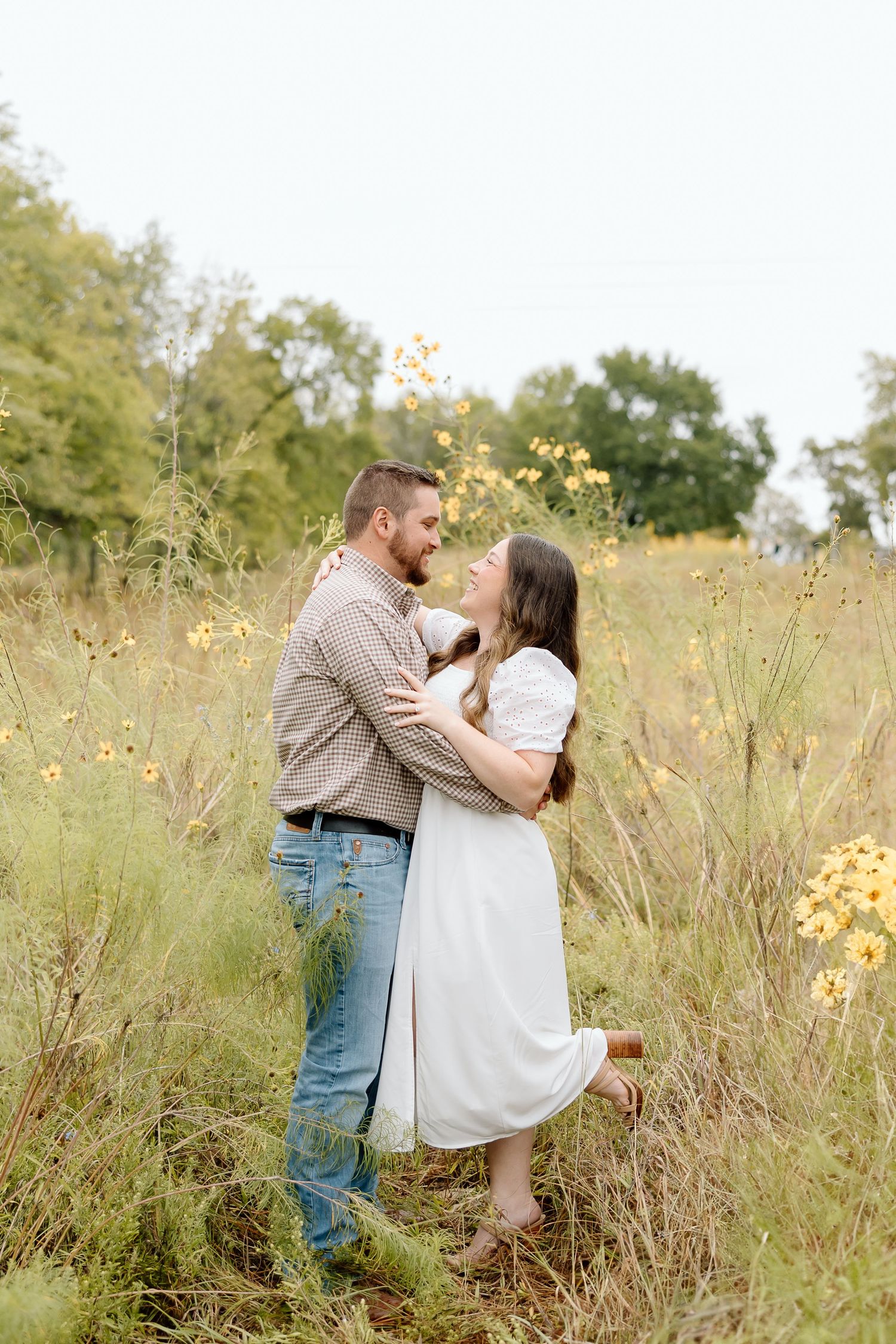 Intimate moment between couple surrounded by blooming wildflowers in golden light.