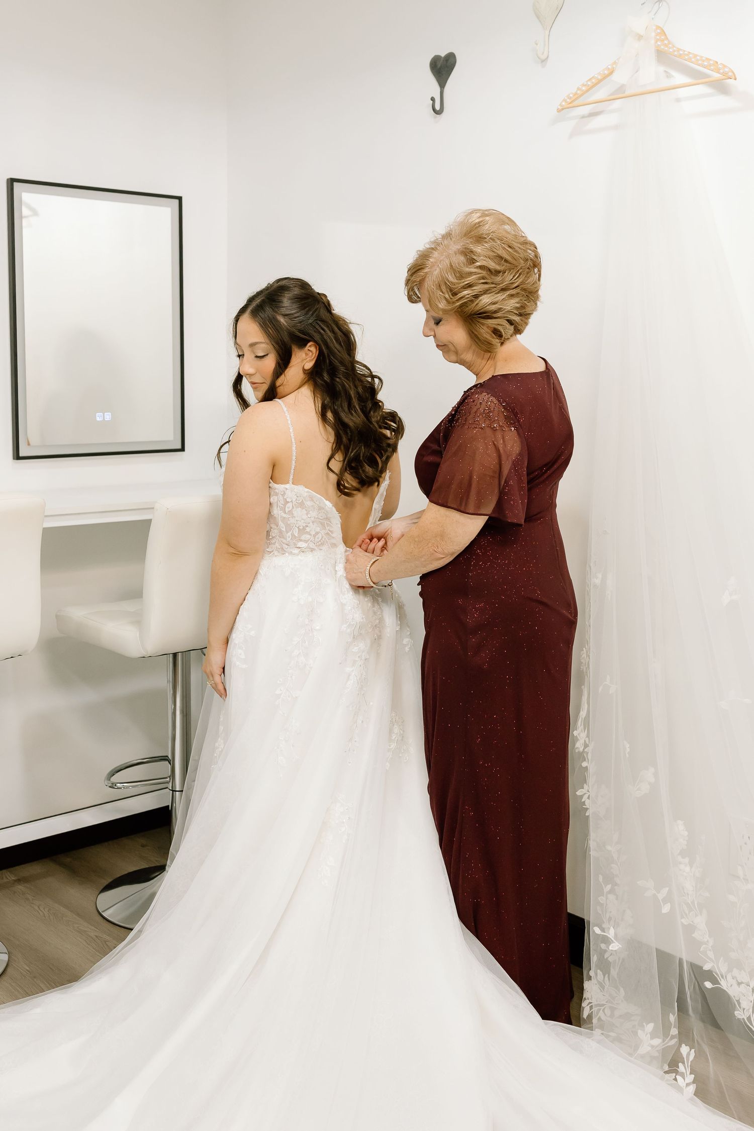 A bride in a flowing white gown is assisted with her dress in a series of wedding preparation photos.