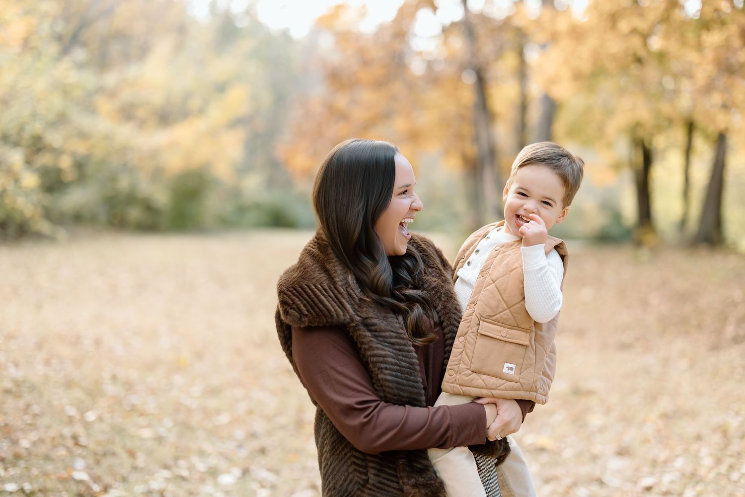 Two people share a joyful moment together outdoors during autumn with golden foliage in the background.