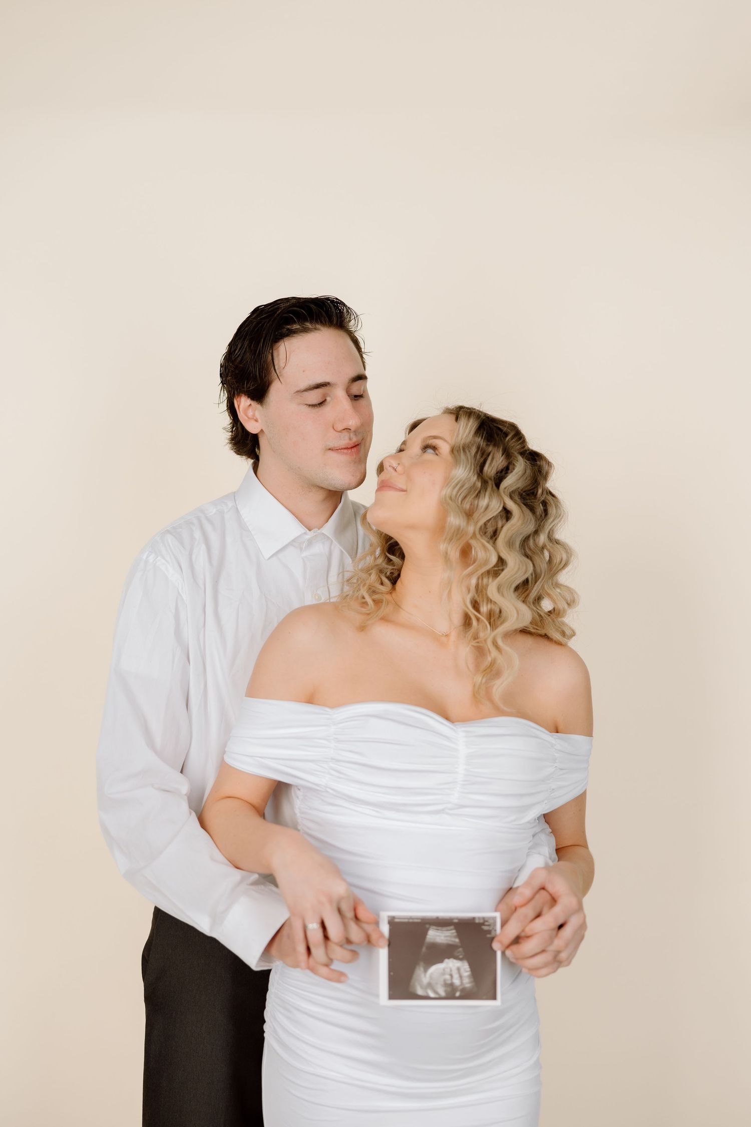 A tender maternity photo captures a couple's joy as they hold an ultrasound picture together.