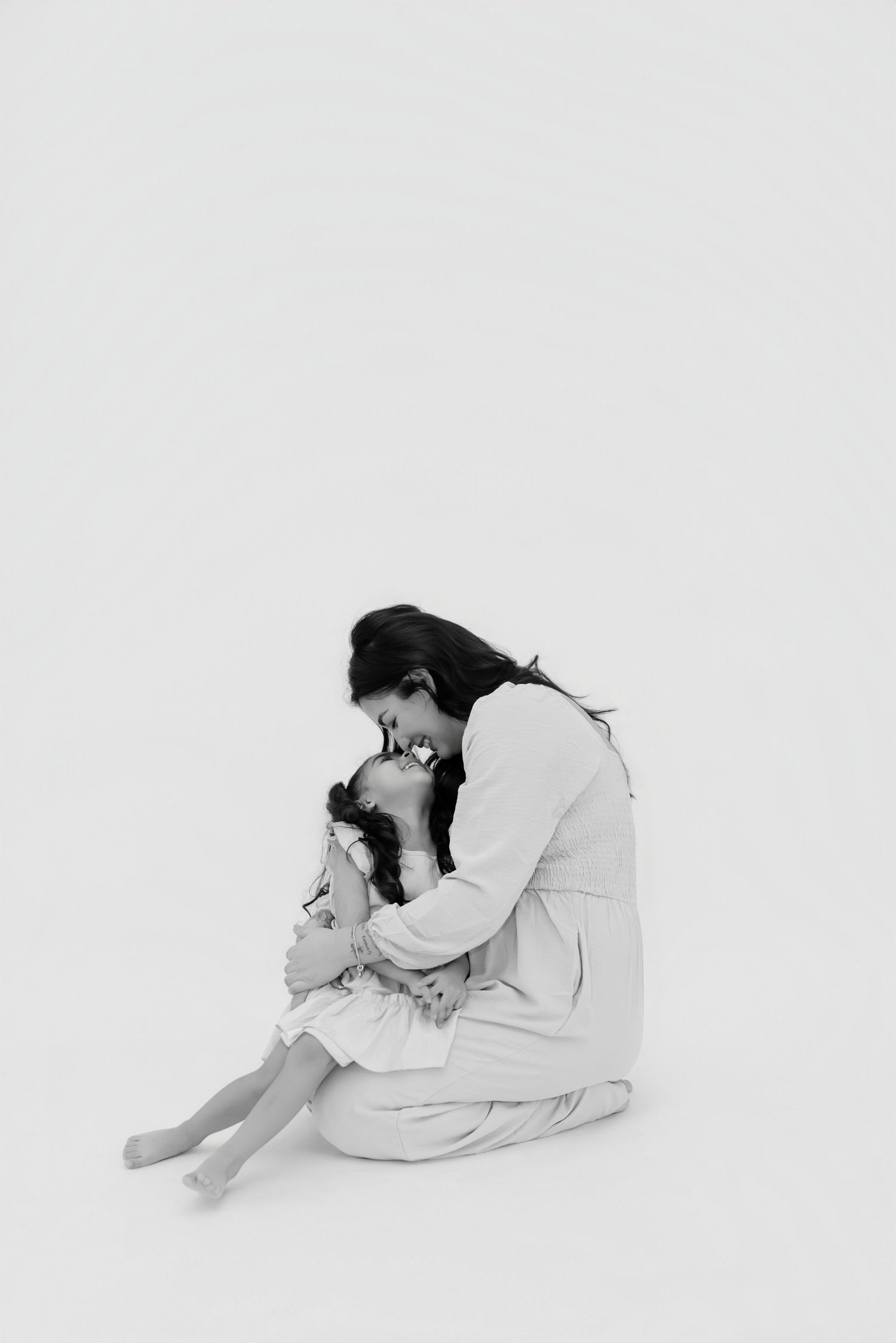 A tender black and white portrait showing an intimate moment of embrace against a white background.