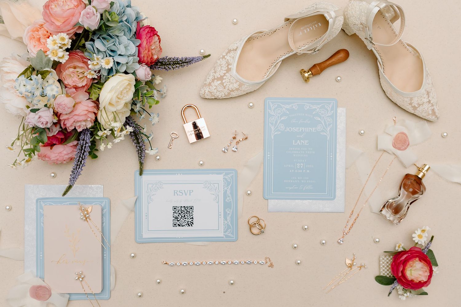 A wedding invitation suite with pink and blue accents, floral arrangements, and delicate ribbon details.