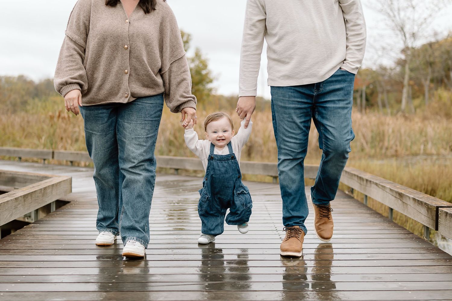 Legs of people walking together on a wooden boardwalk through a natural area in autumn.