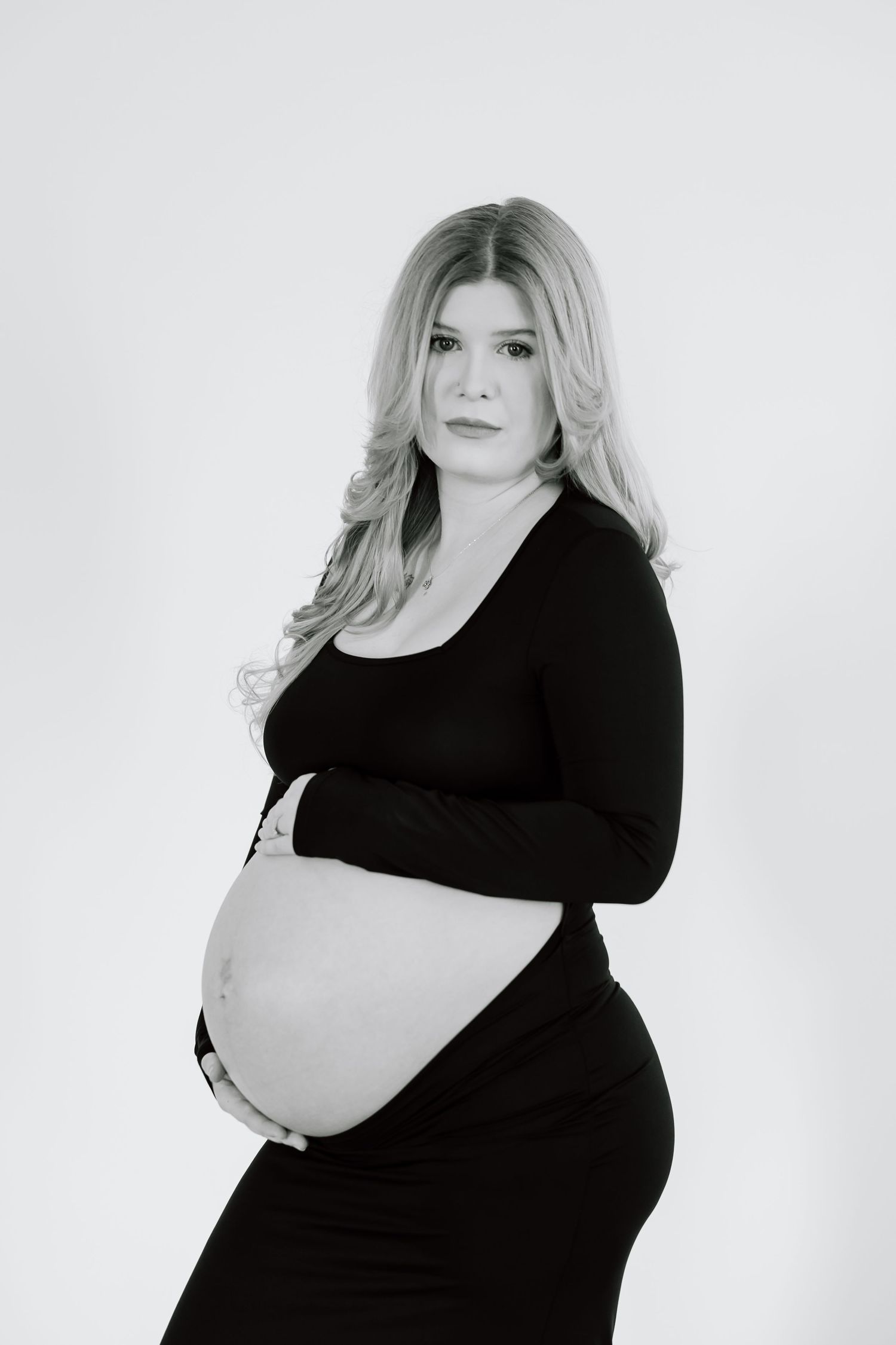 Black and white maternity portrait showcasing an elegant pose against a light background.