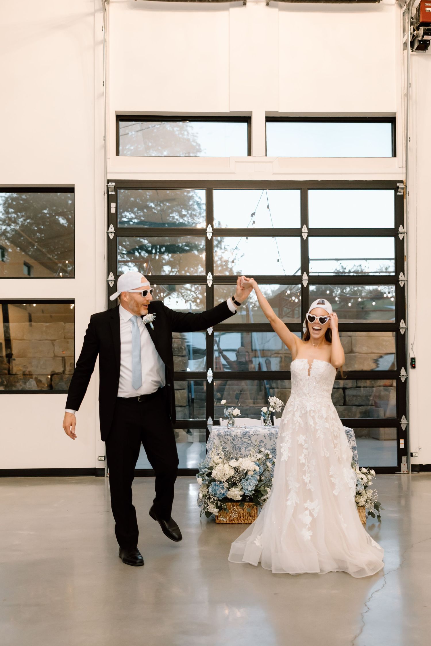 Newlyweds wearing sunglasses celebrating their grand entrance at a modern wedding reception.