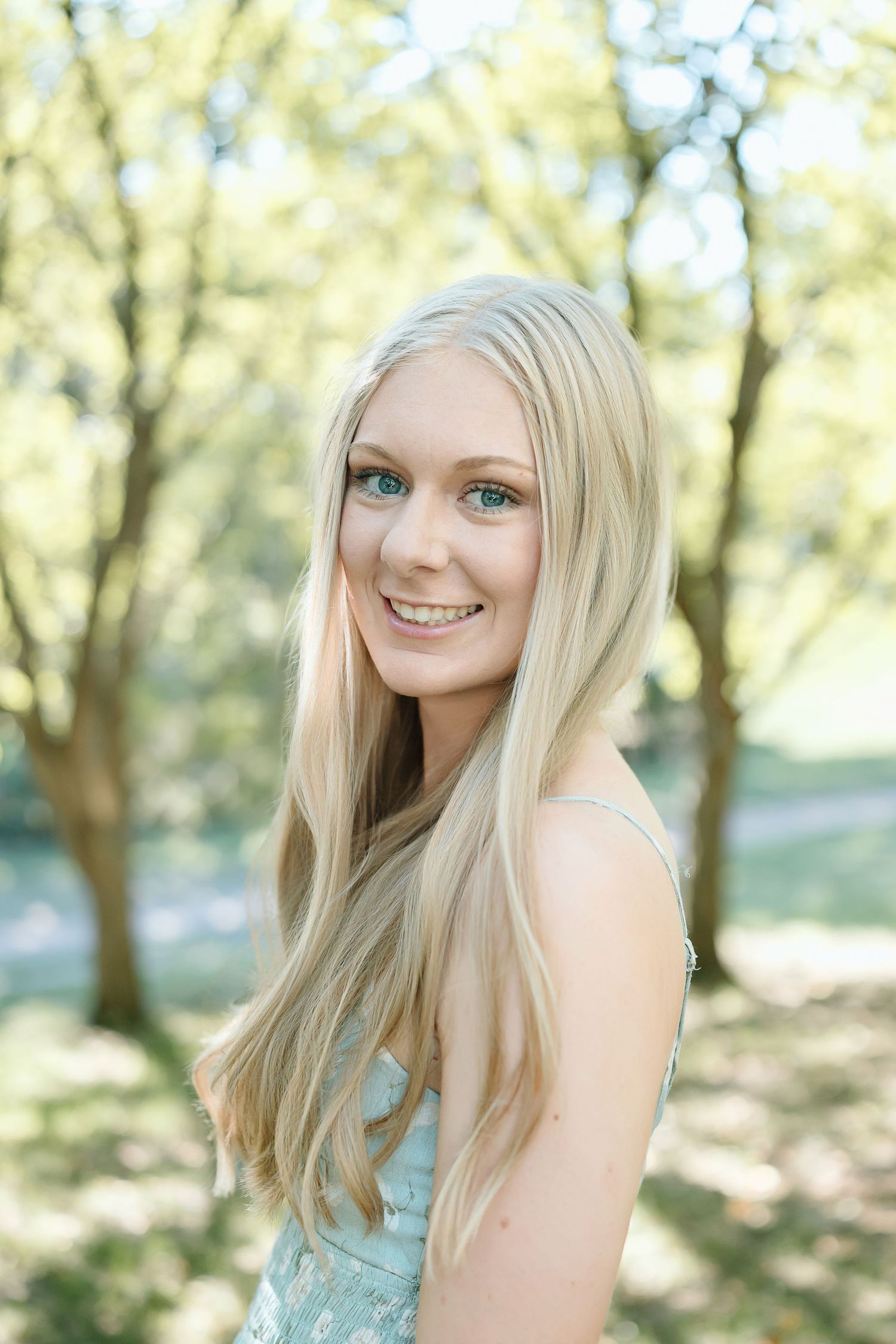 A series of outdoor portraits showing a person with long blonde hair wearing a light blue top in a sunlit wooded setting.