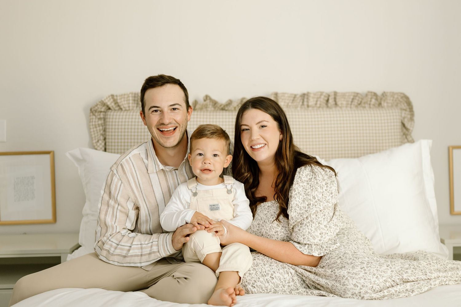 Family wearing matching white and beige striped pajamas relaxing together in bed.