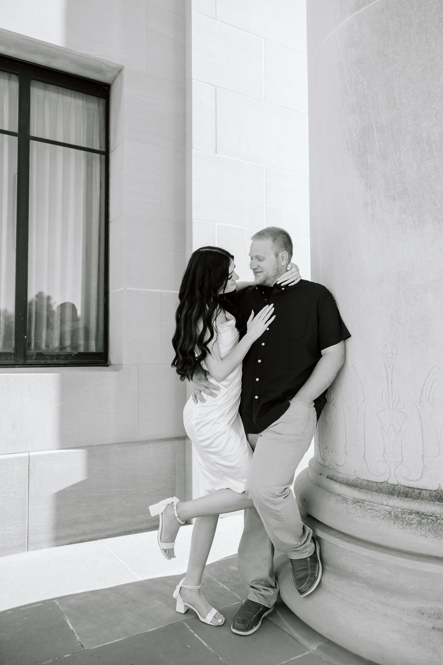 Black and white photo series showing two people playfully interacting in a minimalist architectural setting.