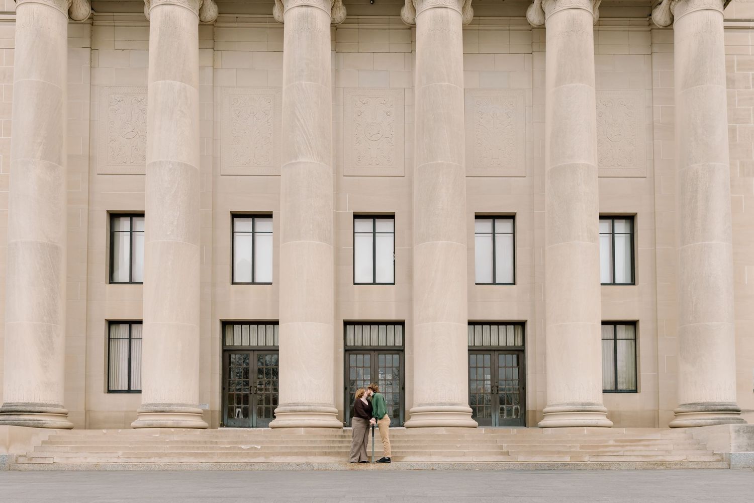 Classical stone columns and windows line the exterior facade of a grand government or institutional building.