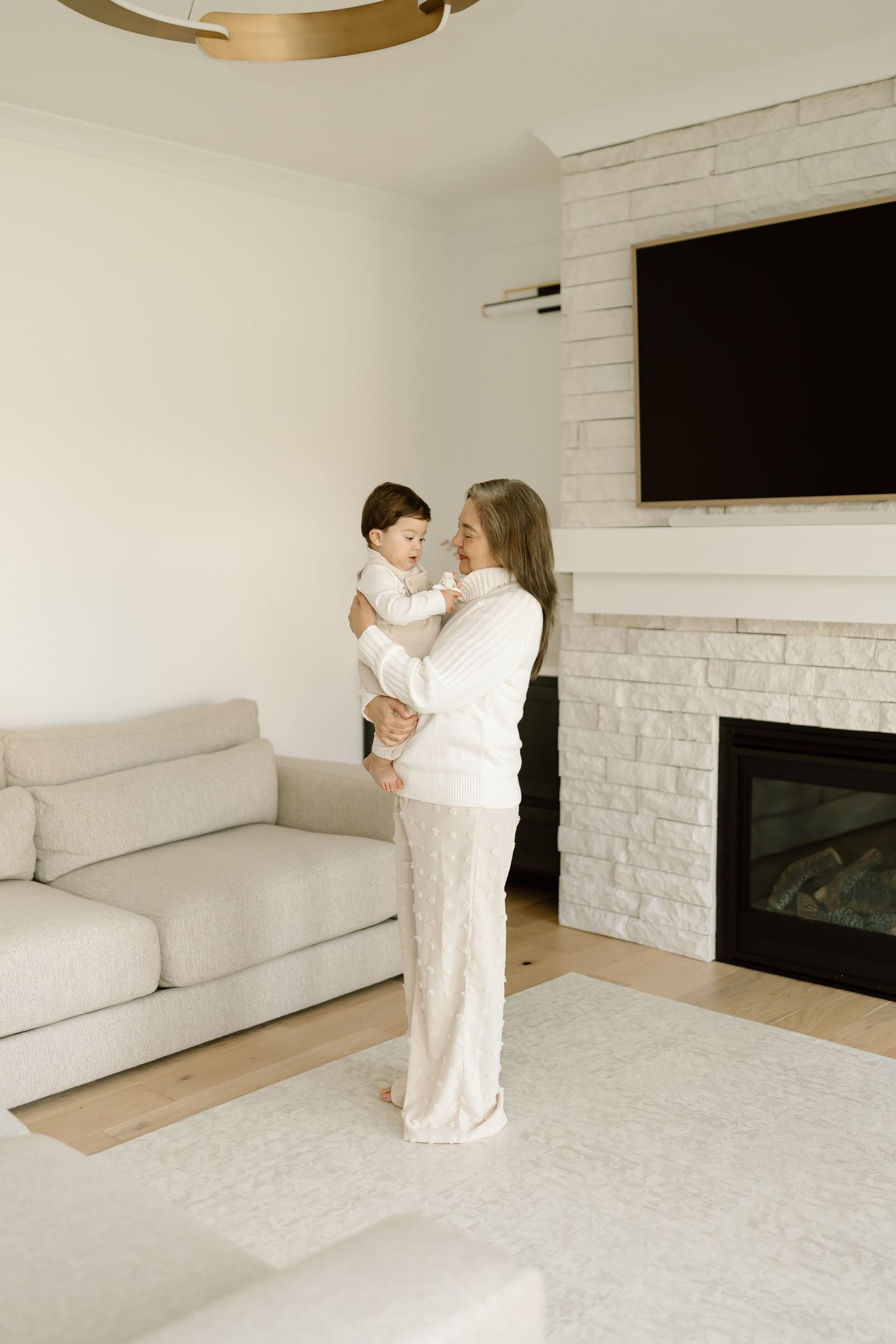 A minimalist white living room features a modern fireplace and cozy seating area with tender family moments captured.