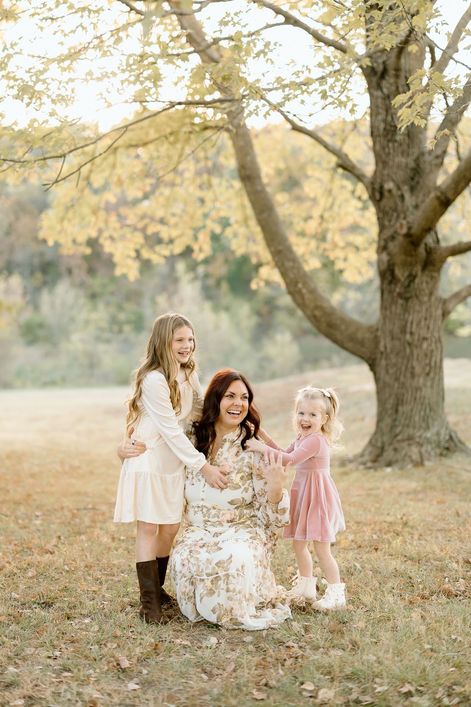A heartwarming autumn family portrait under a golden-leaved tree in a dreamy outdoor setting.