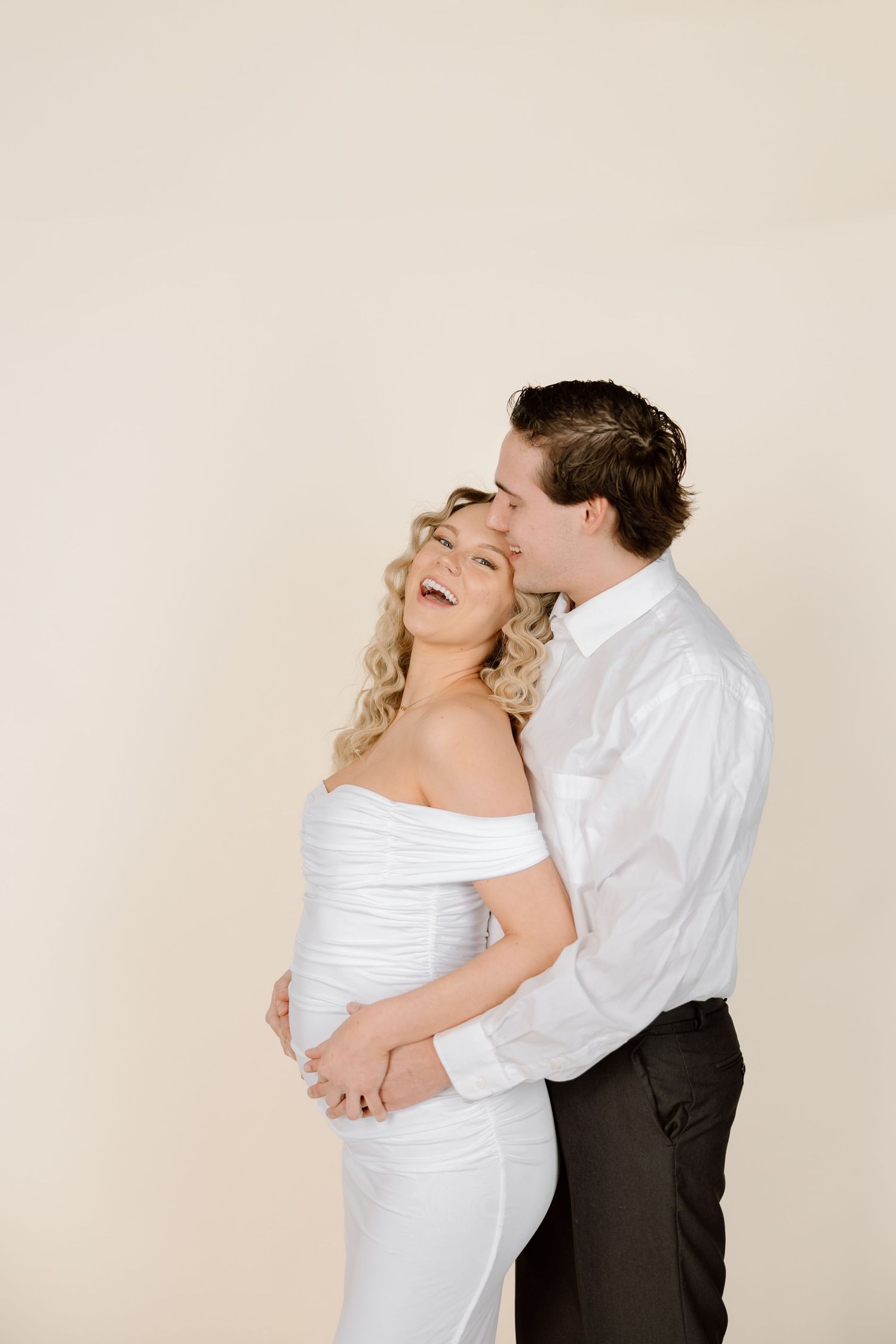 A couple in wedding attire embraces and laughs together in a series of romantic poses against a light background.