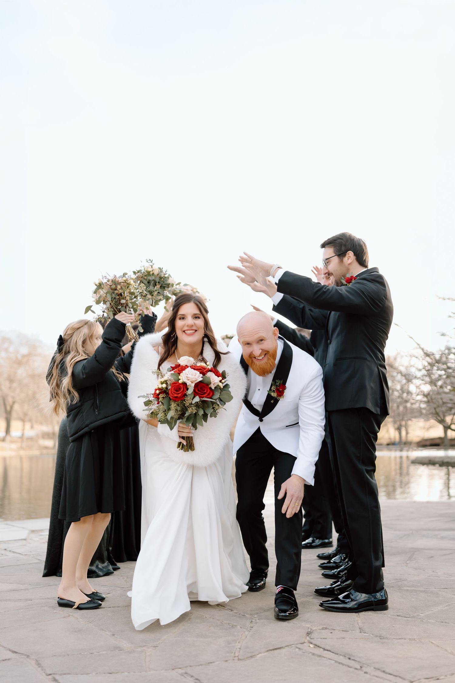 A wedding party poses in a sequence of playful dipping poses on a paved walkway.