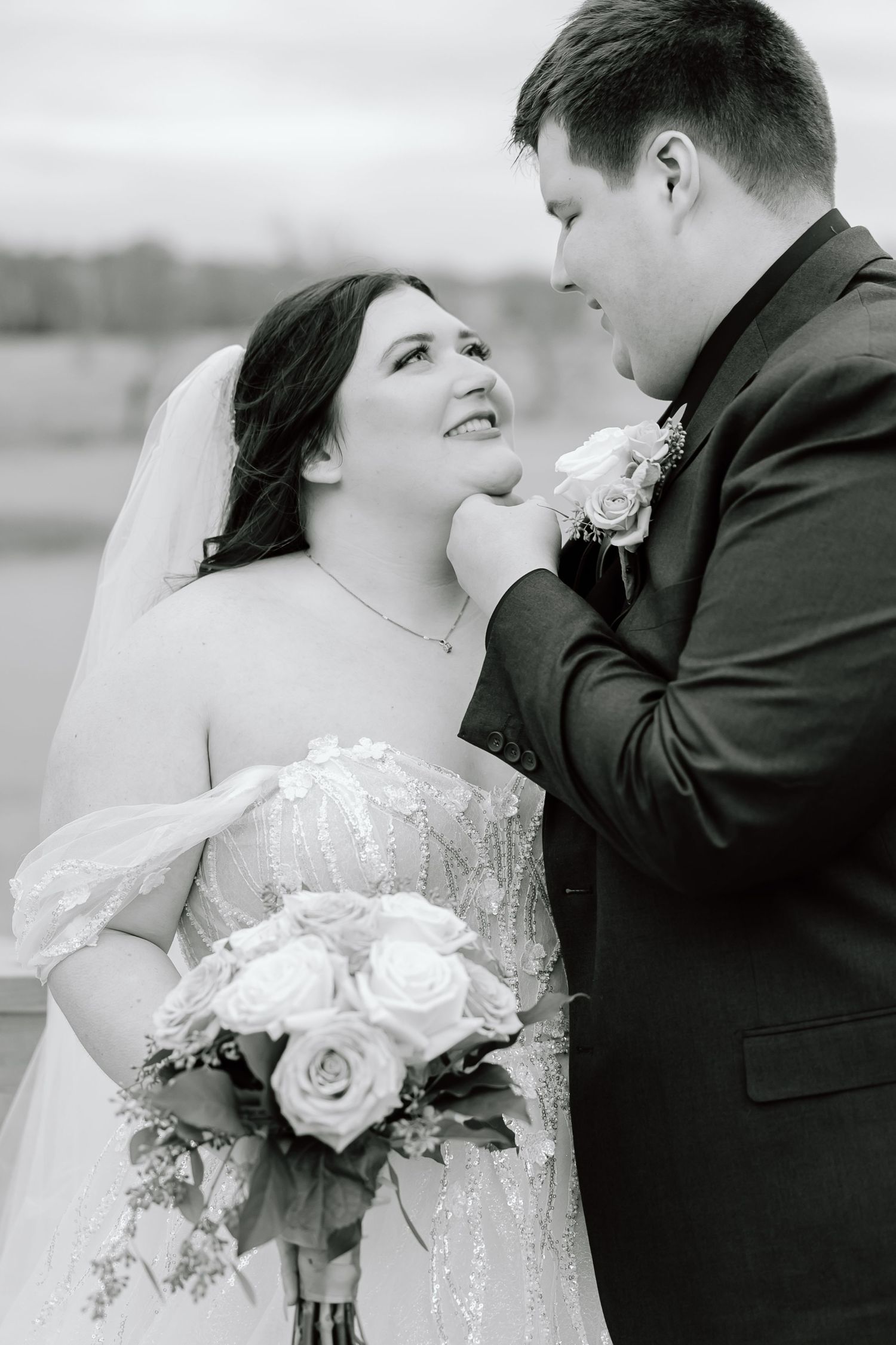 Black and white intimate wedding portrait with elegant floral bouquet.