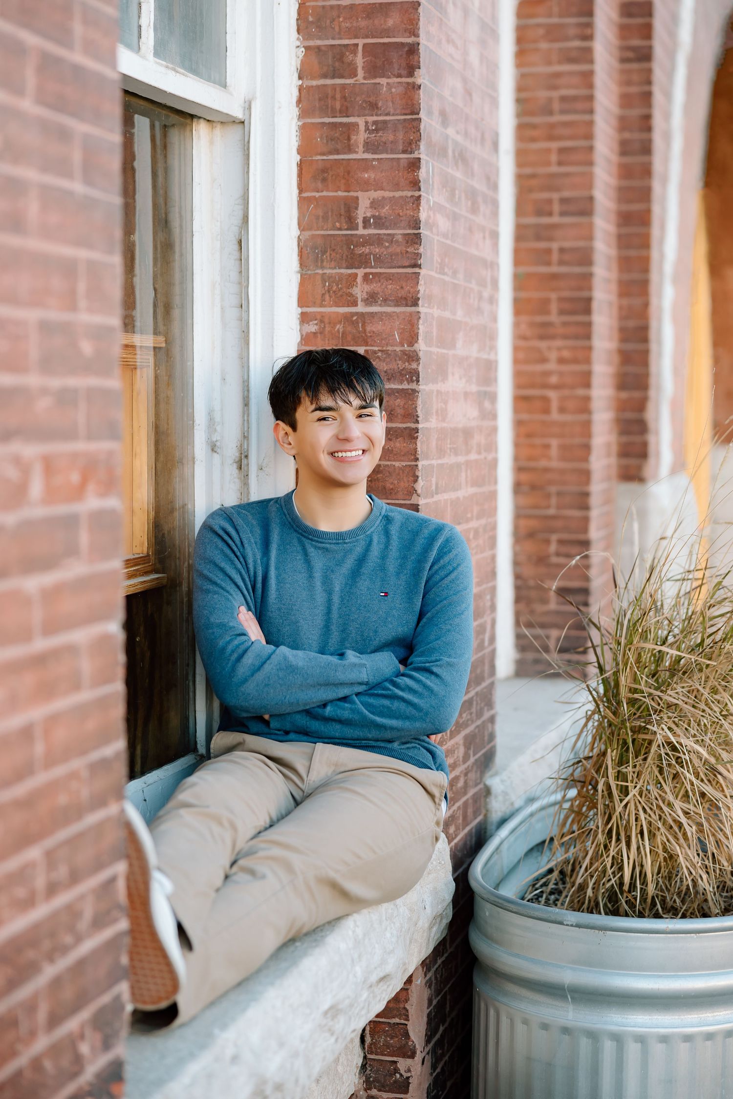 Cheerful outdoor portrait sitting on stone ledge by storefront.