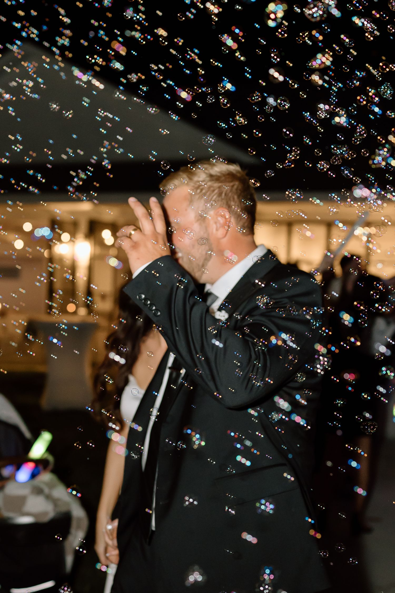 A couple shares a romantic kiss at a wedding celebration while confetti falls around them in a magical moment.