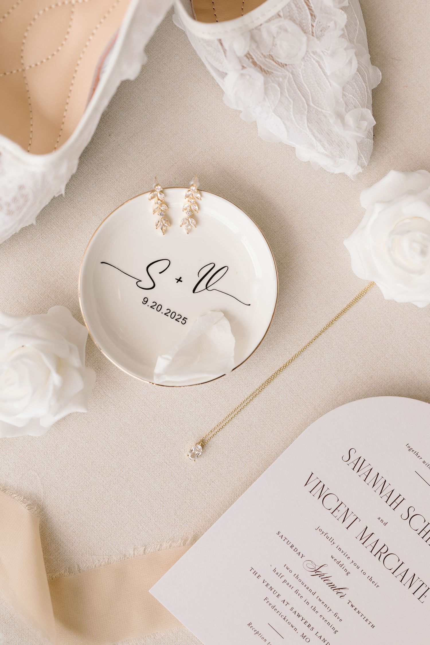 Elegant wedding stationery with white paper flowers and delicate calligraphy on cream colored background.