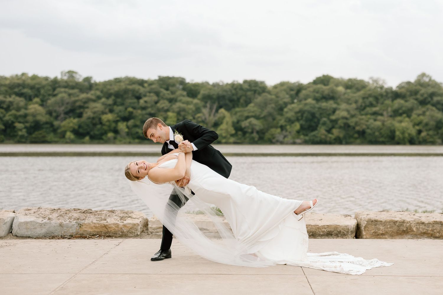 A series of minimalist wedding photos showing graceful poses along a waterfront stone wall.