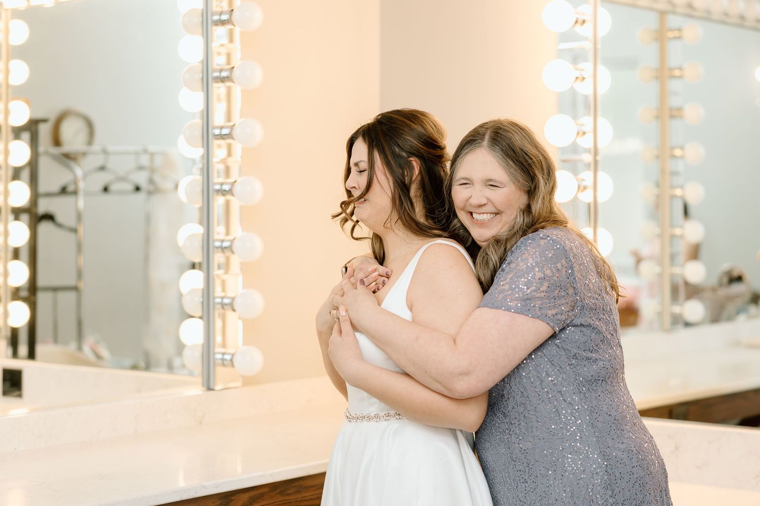 A couple shares a romantic moment in front of illuminated mirrors in a bright studio setting.