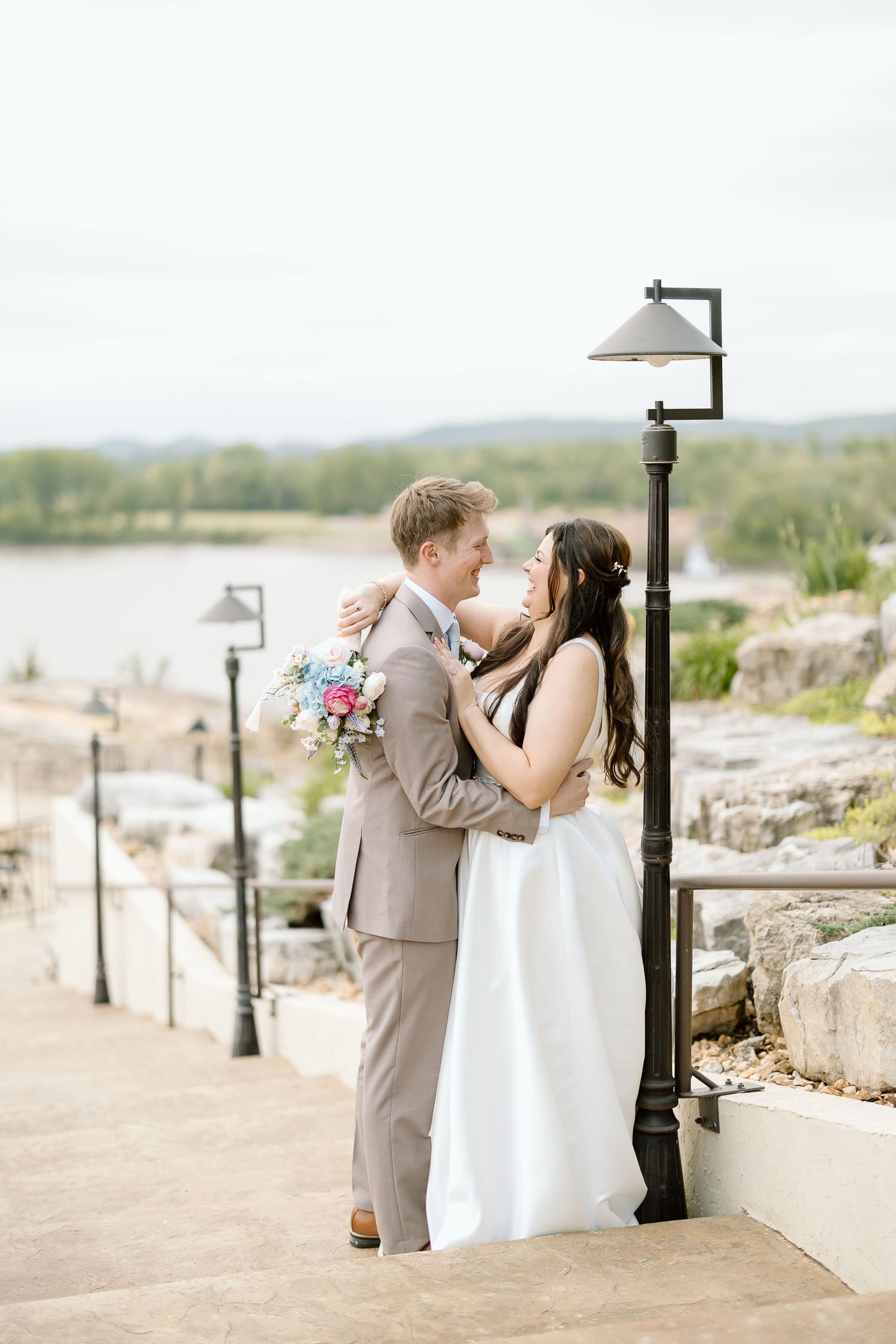 Romantic wedding couple shares tender moments together on a stone path overlooking a scenic landscape.