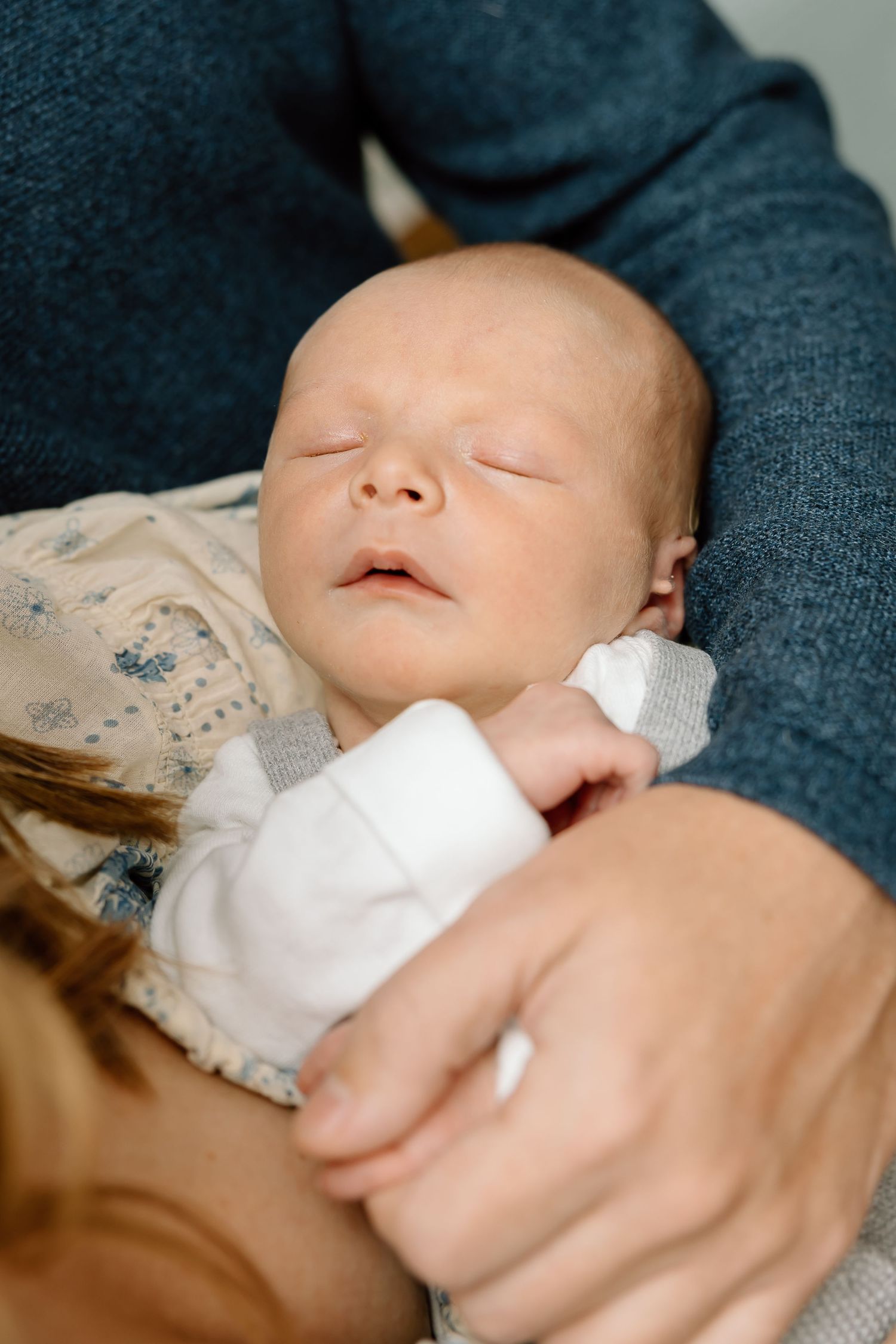 A sleeping baby rests peacefully on a dark blue surface with a white blanket.