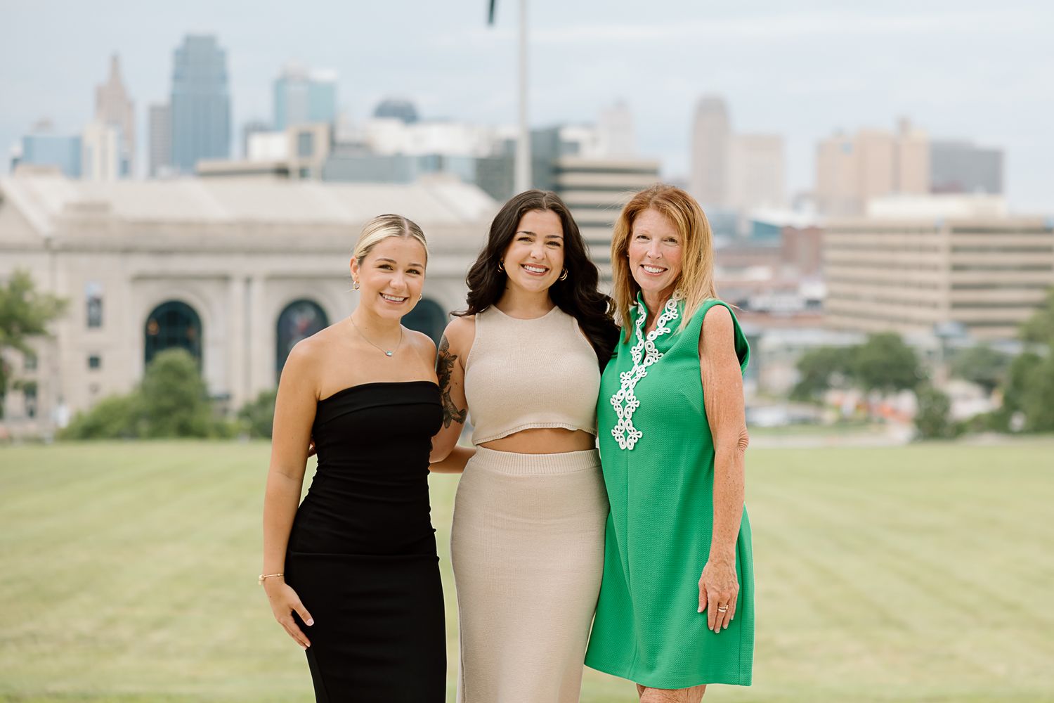 Group of friends posing together outdoors with city skyline visible in the background.