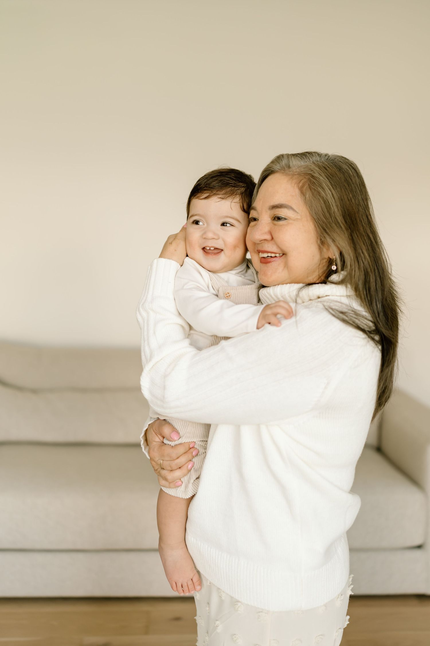 A joyful moment shared between parent and child wearing matching white outfits while embracing and laughing together.