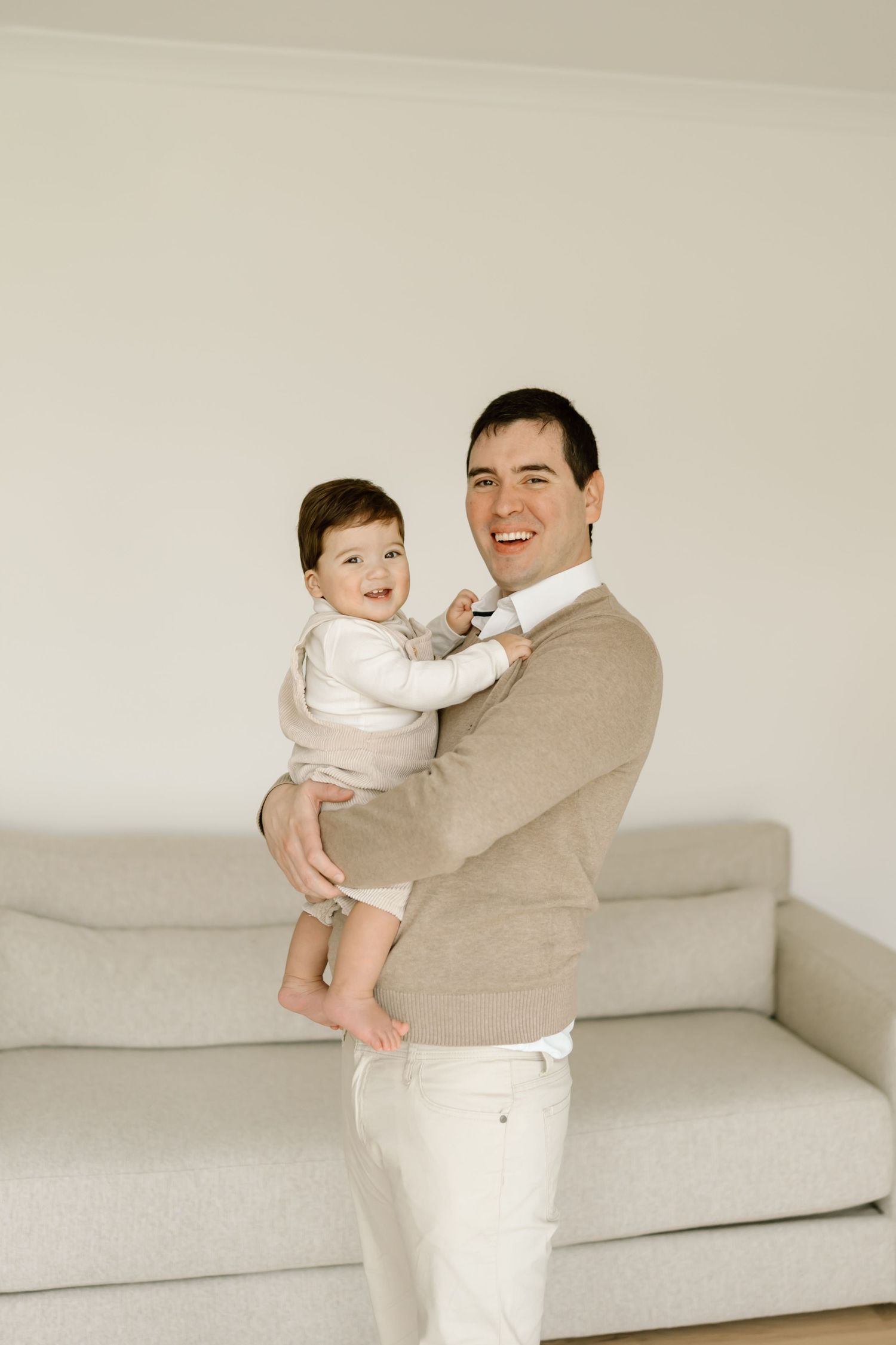 A series of four connected photos showing playful interaction between an adult and baby on a white couch.