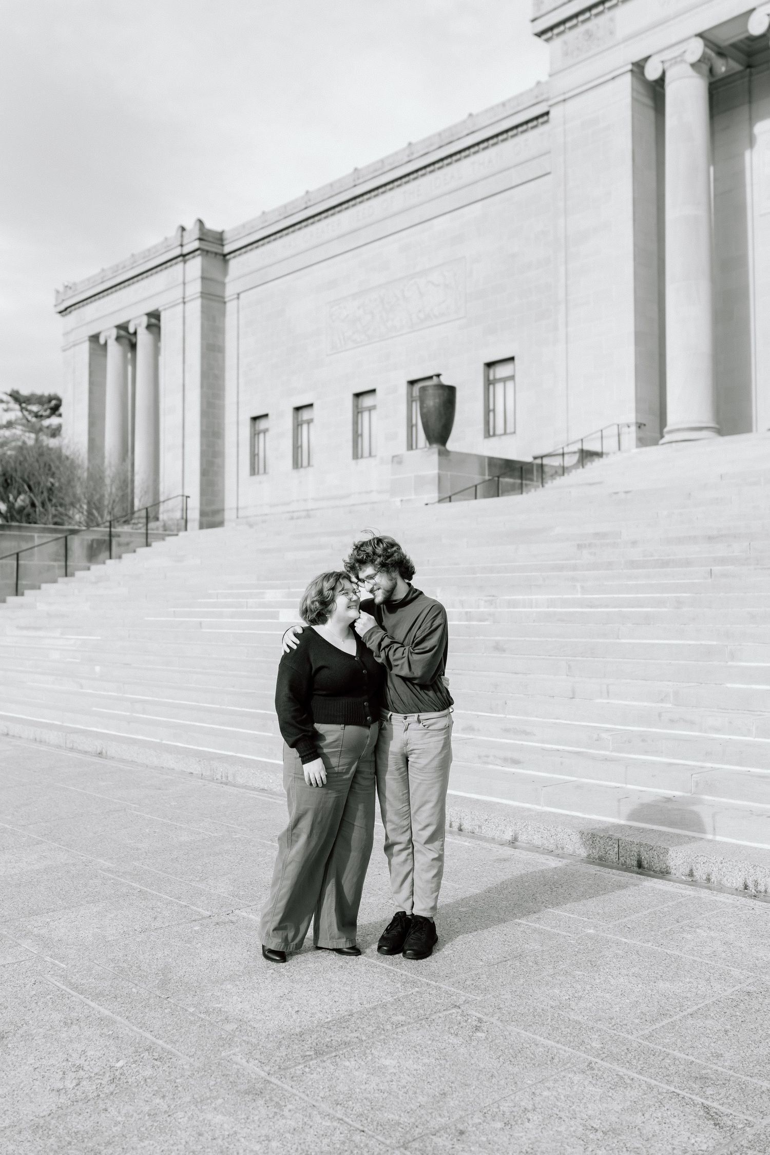 A sequence of black and white photographs showing two people embracing on the steps of a grand building with columns.