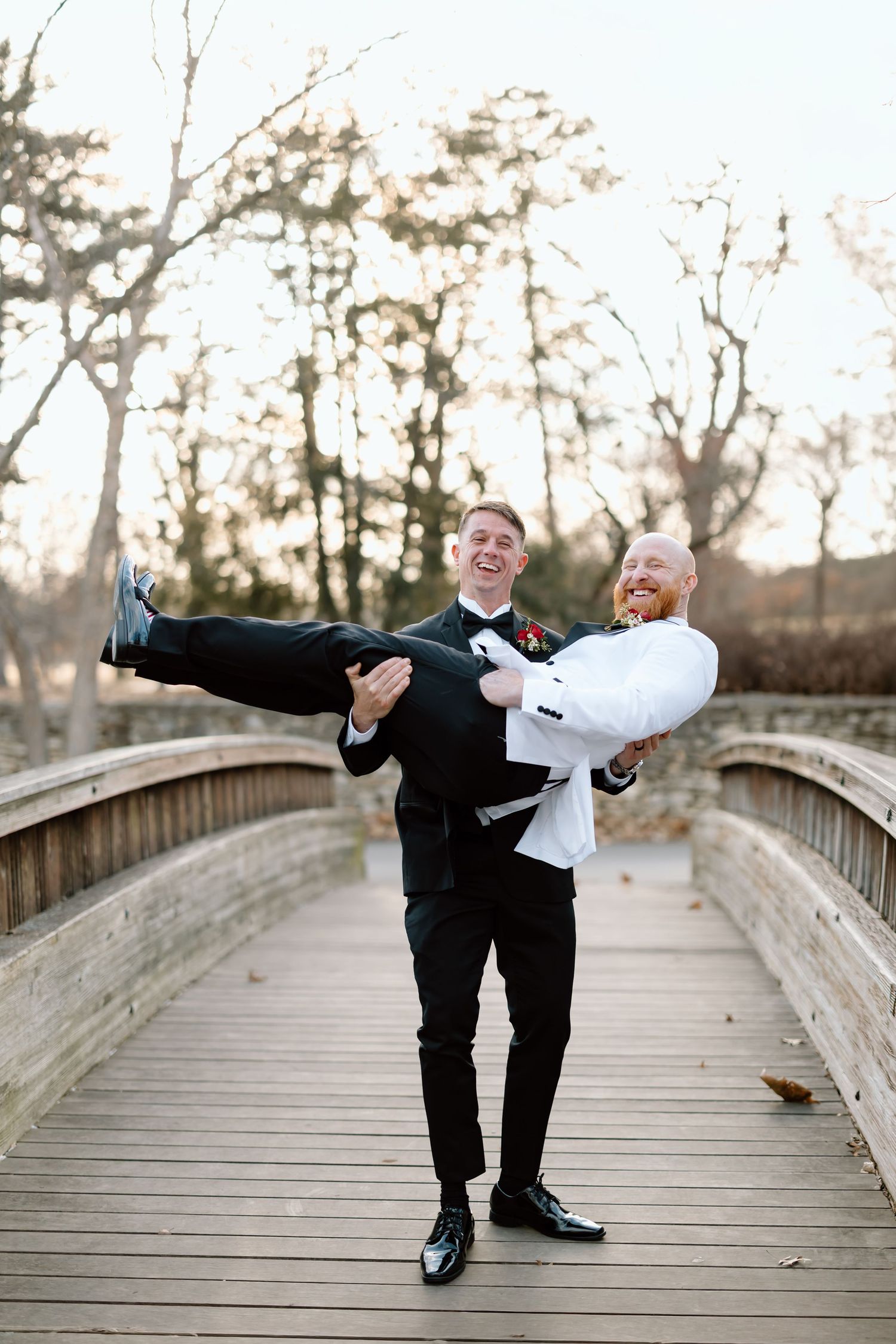 A joyful moment captured on a wooden bridge during a formal event as one person lifts another in celebration.