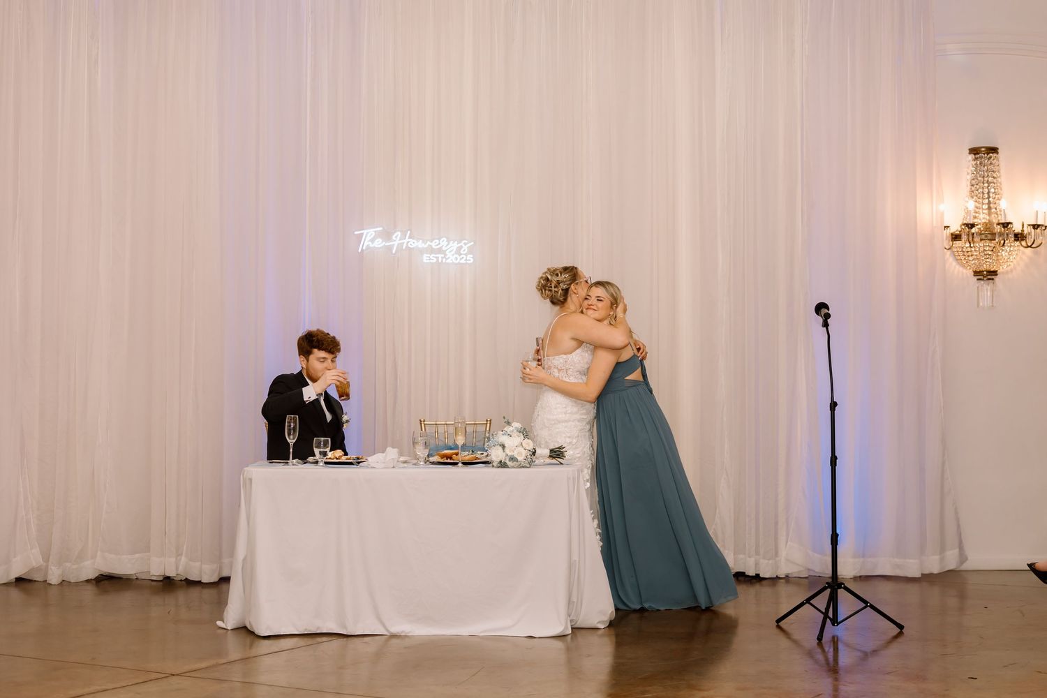 Wedding reception venue setup with white drapes, elegant lighting, and tables arranged for a formal celebration.