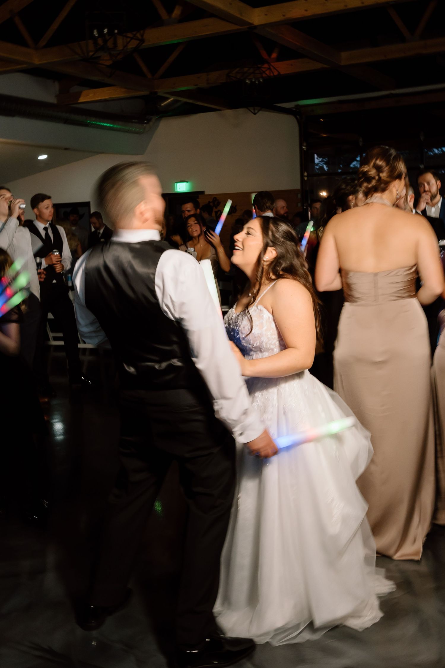 Wedding guests dance together in a dimly lit reception venue during a romantic slow dance moment.
