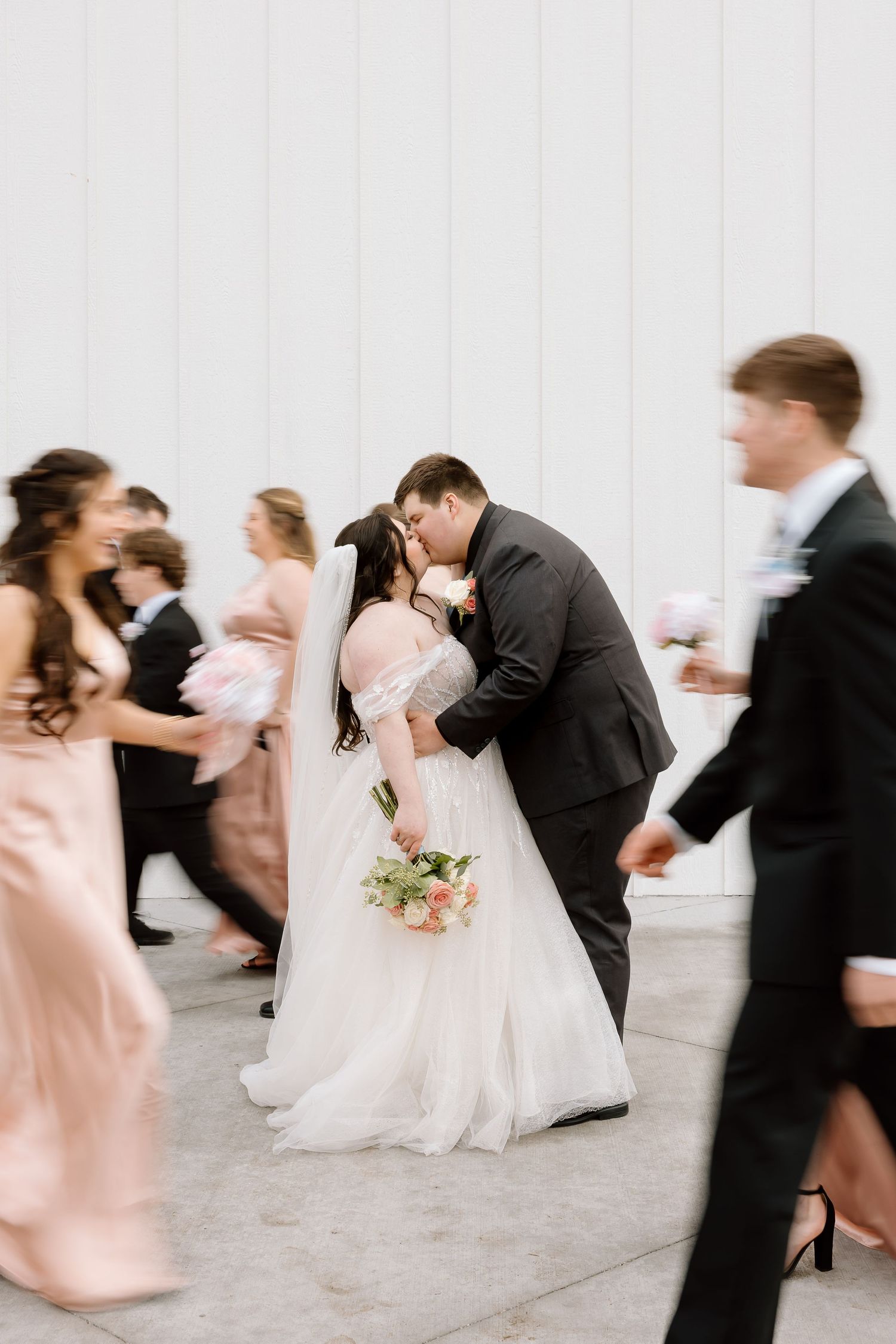 Motion-blurred snapshot of wedding party dancing and celebrating outdoors.