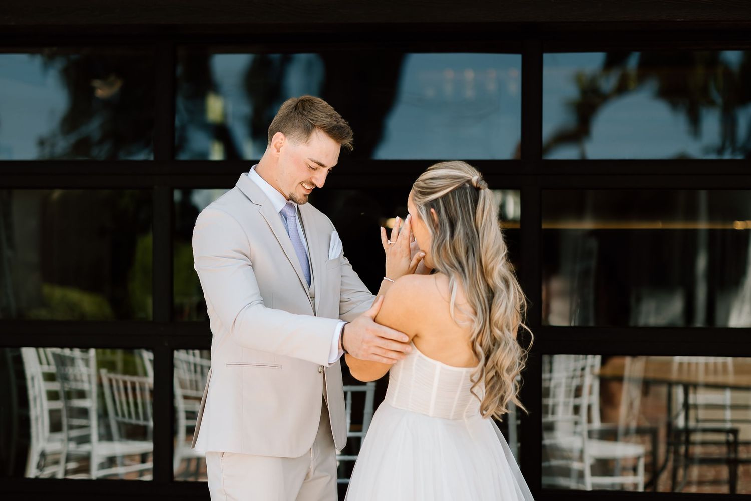 First look moment between couple outside venue with white rocking chairs in background.