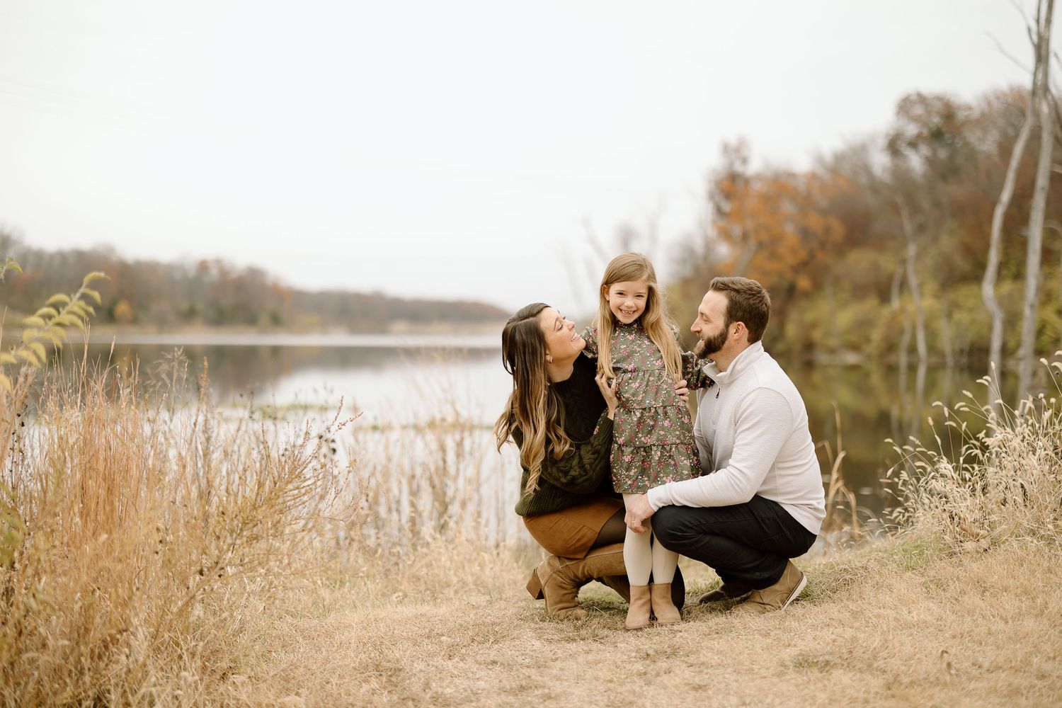 Intimate family portrait by lakeside with fall colors and natural lighting.