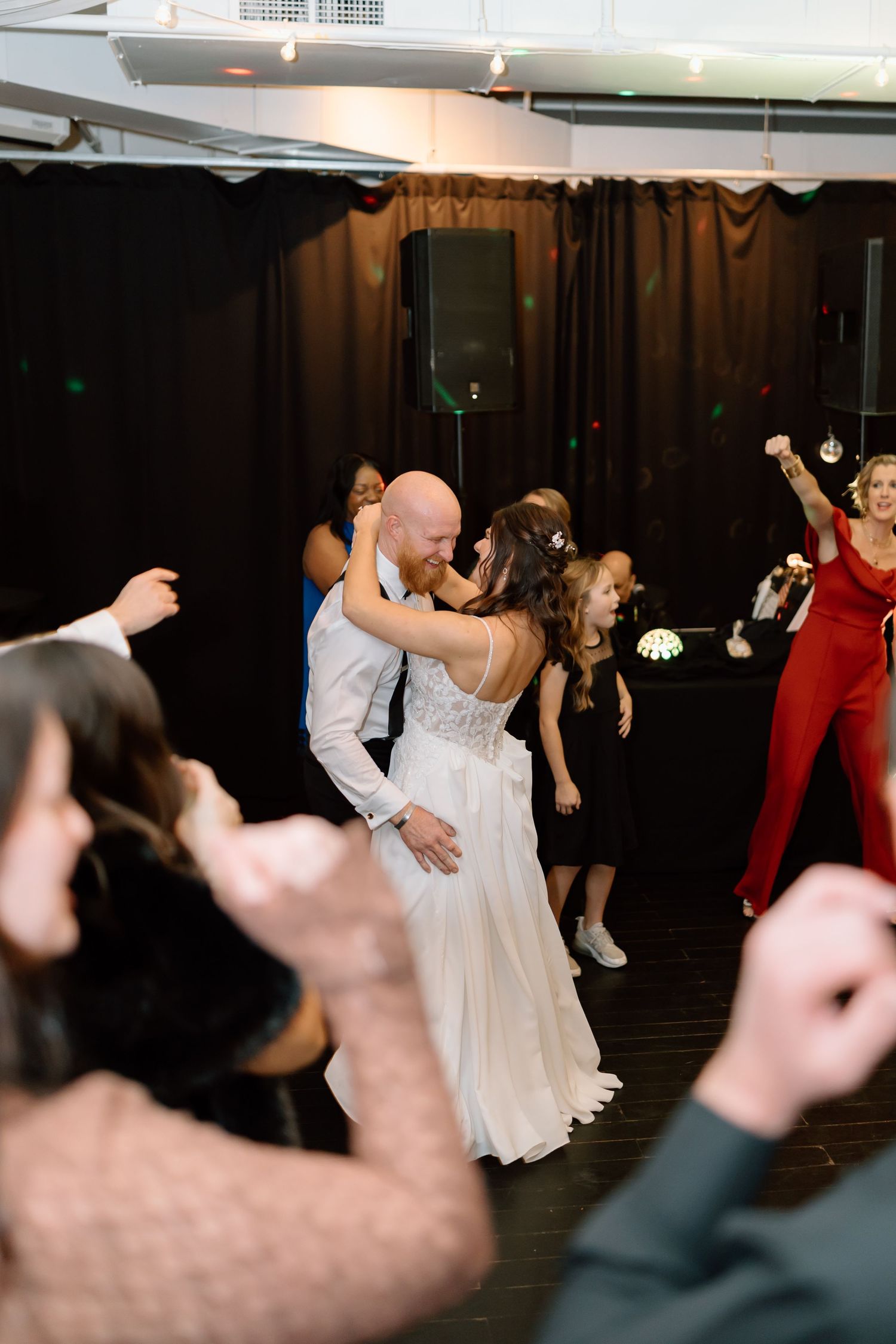 Wedding guests dancing and celebrating on a dimly lit dance floor at a reception party.