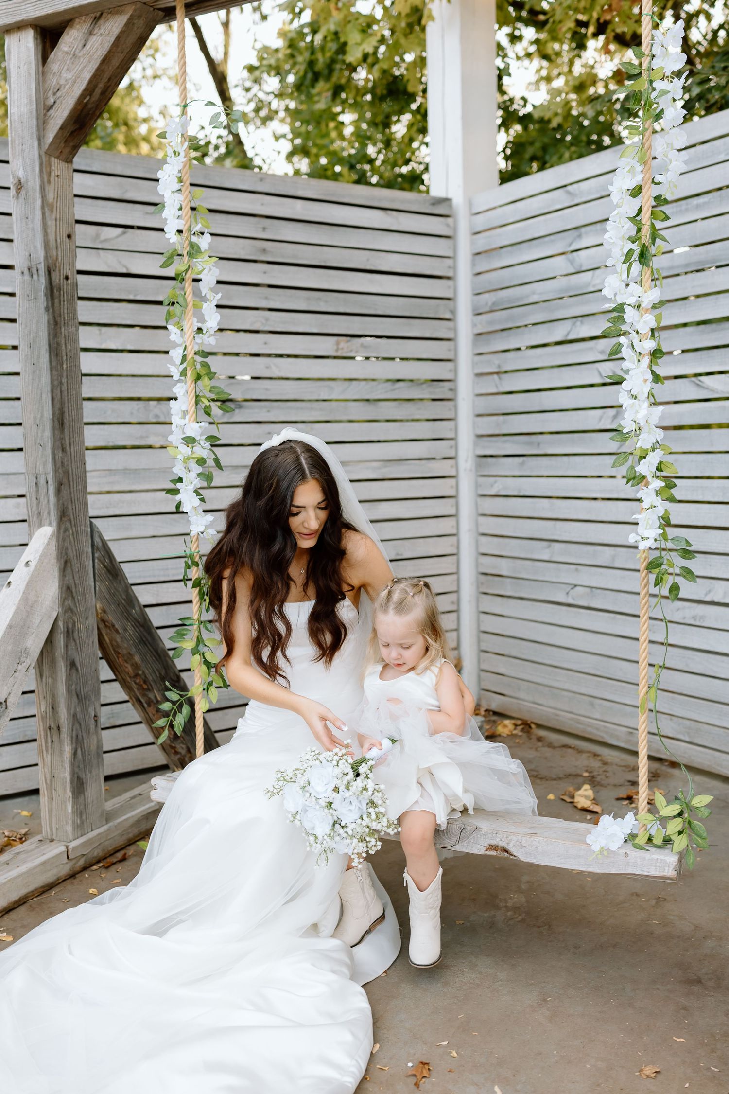 A tender moment captured in a rustic white wooden setting with floral vines hanging down.