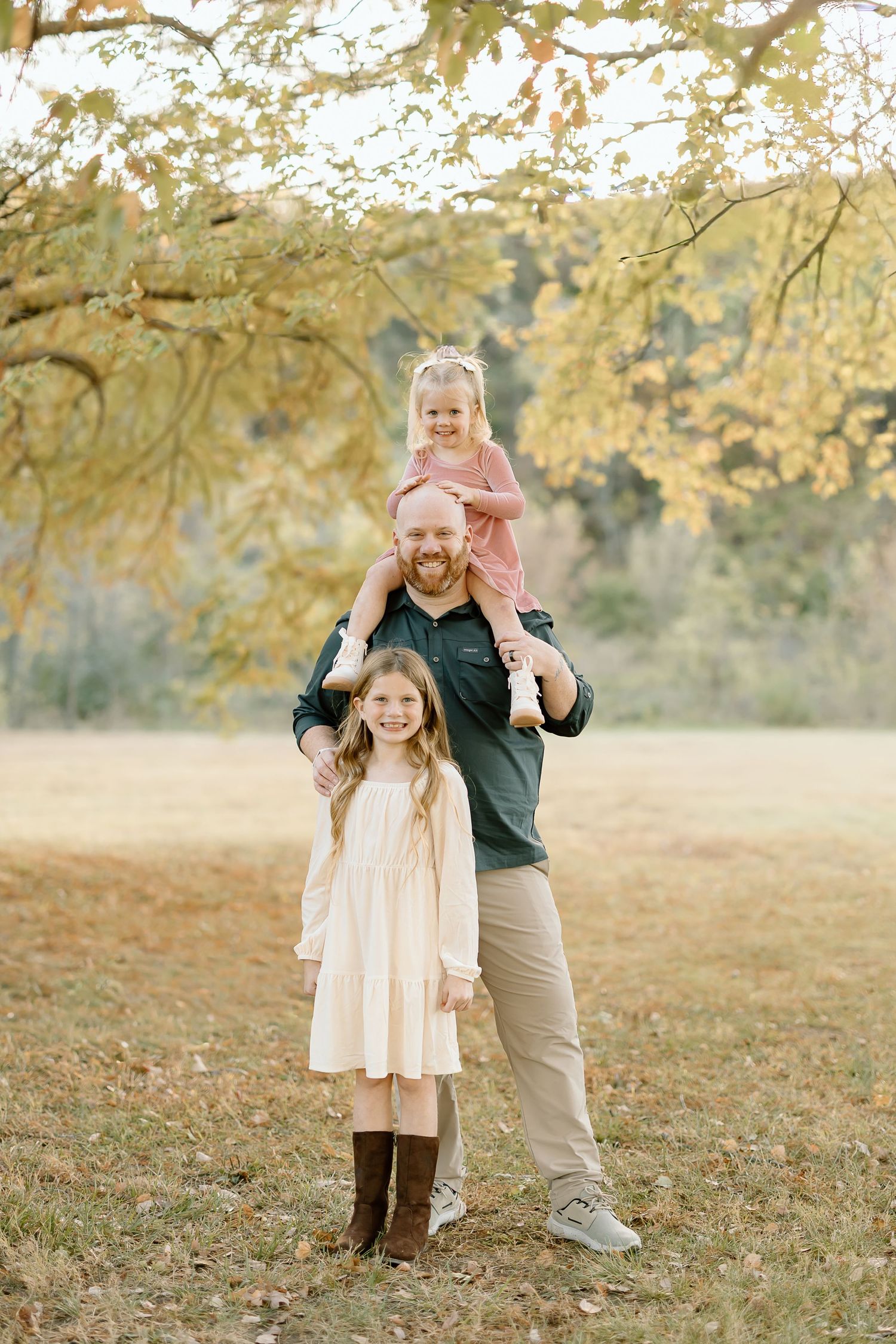 A parent and child share a joyful moment together in a sunlit autumn field with golden foliage.