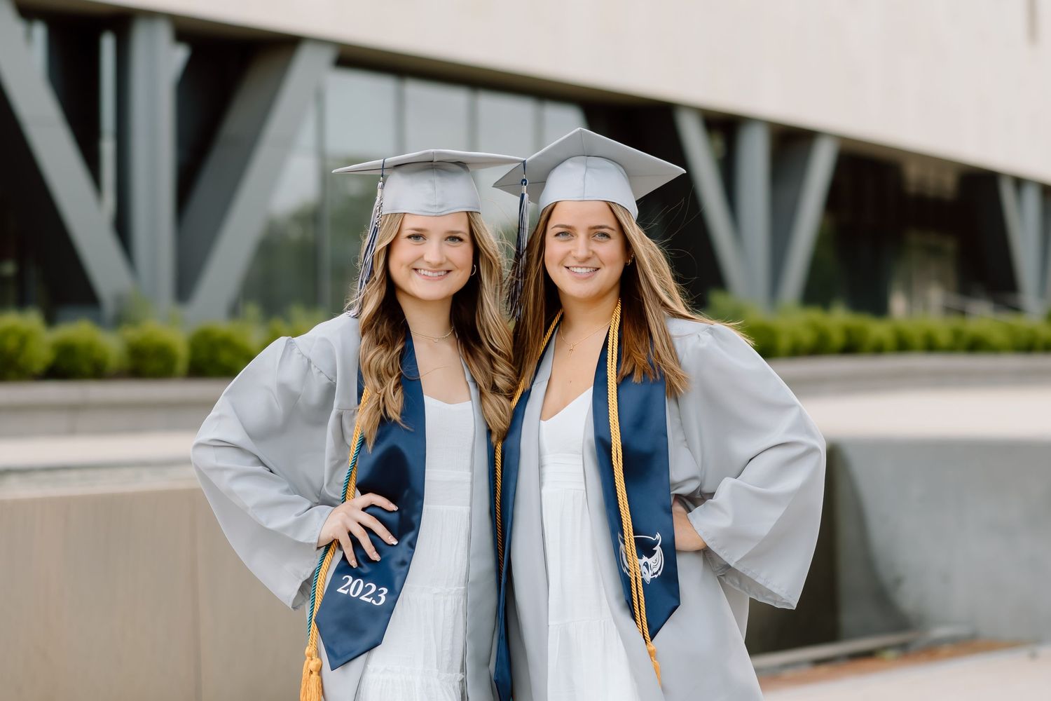 A group of students in matching graduation gowns and caps celebrate together on campus.