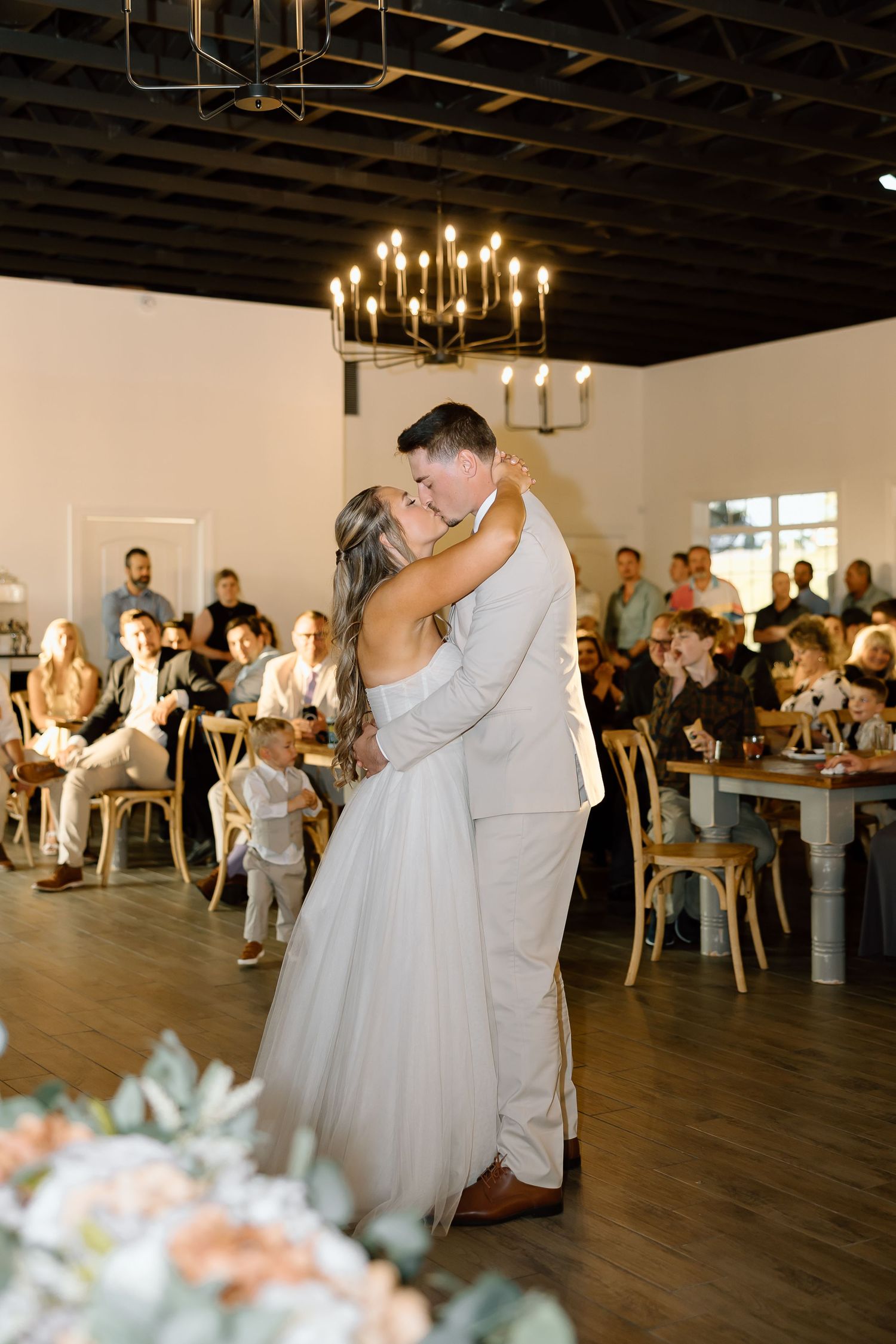 A couple shares their first dance at an elegant reception venue with guests watching.