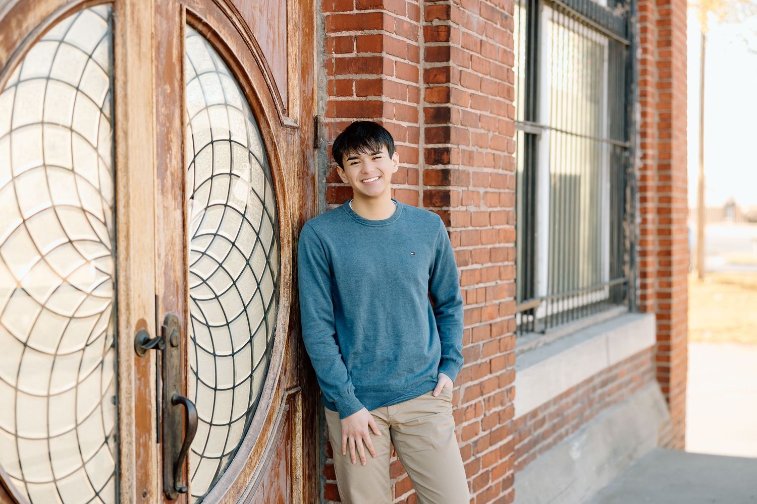 Portrait against historic brick building with ornate circular door design.