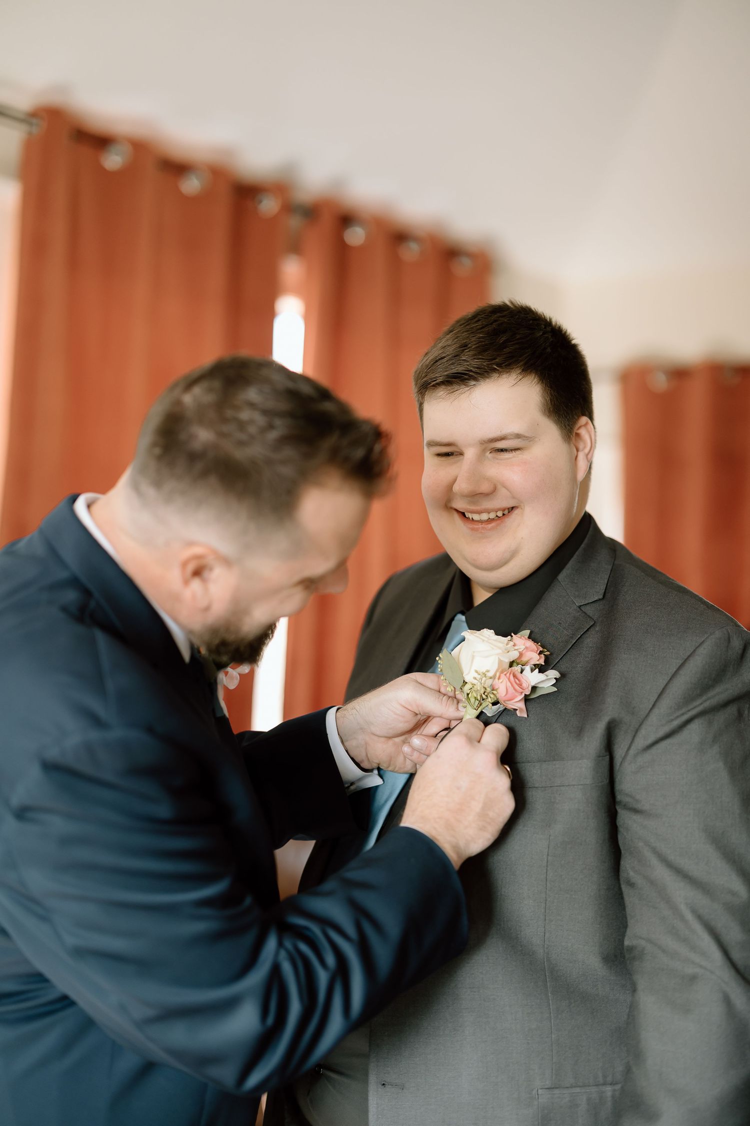 A series of candid moments showing a groomsman pinning a boutonniere onto another groomsman's lapel at a wedding.