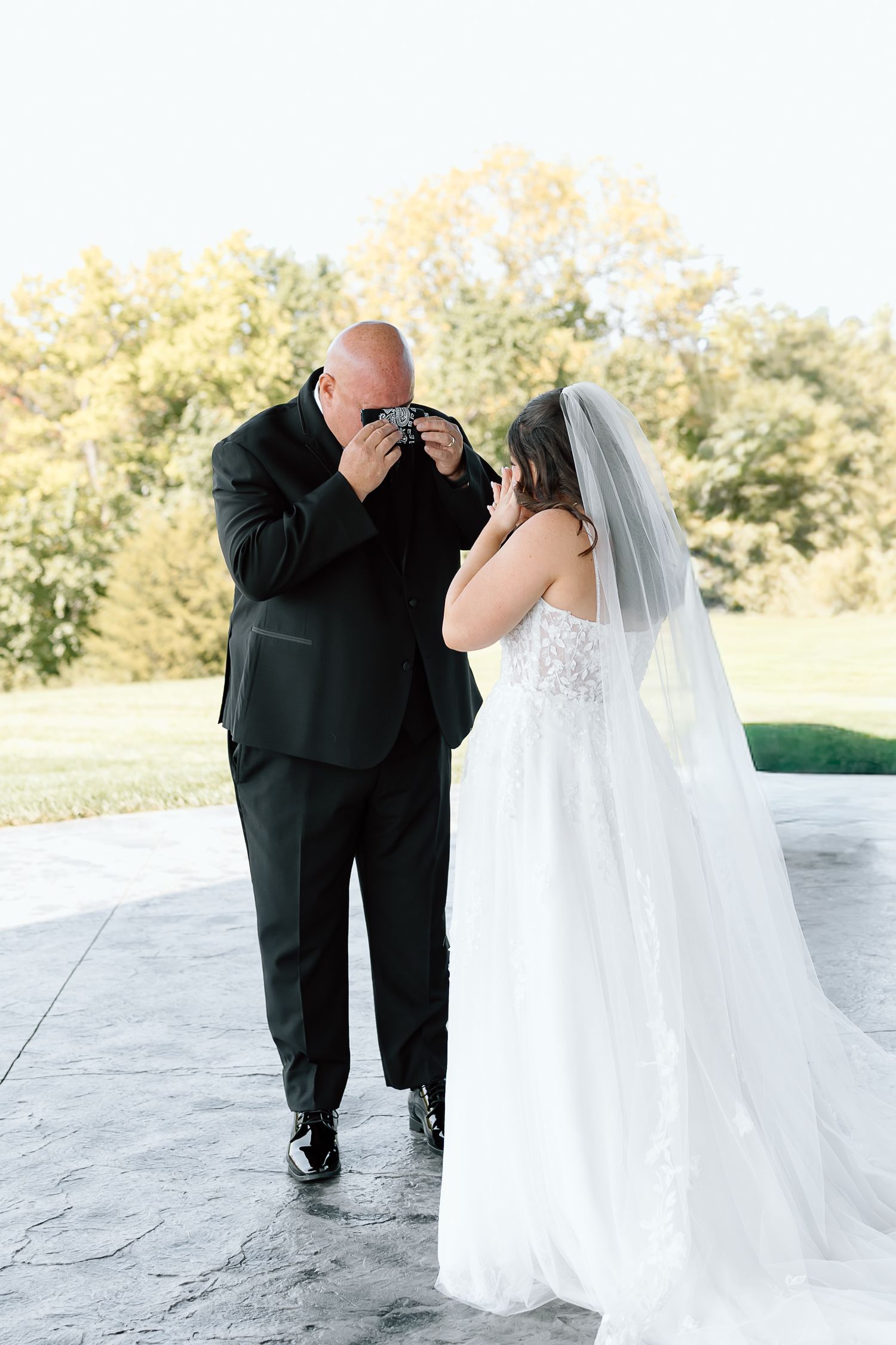 A wedding couple shares a romantic dance together on an outdoor patio surrounded by greenery.