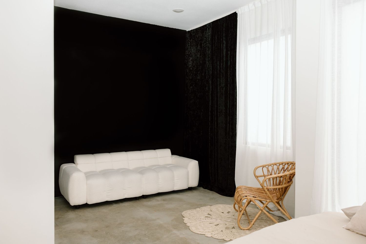 A minimalist white room interior with a bamboo chair and white curtains features clean lines and natural lighting.