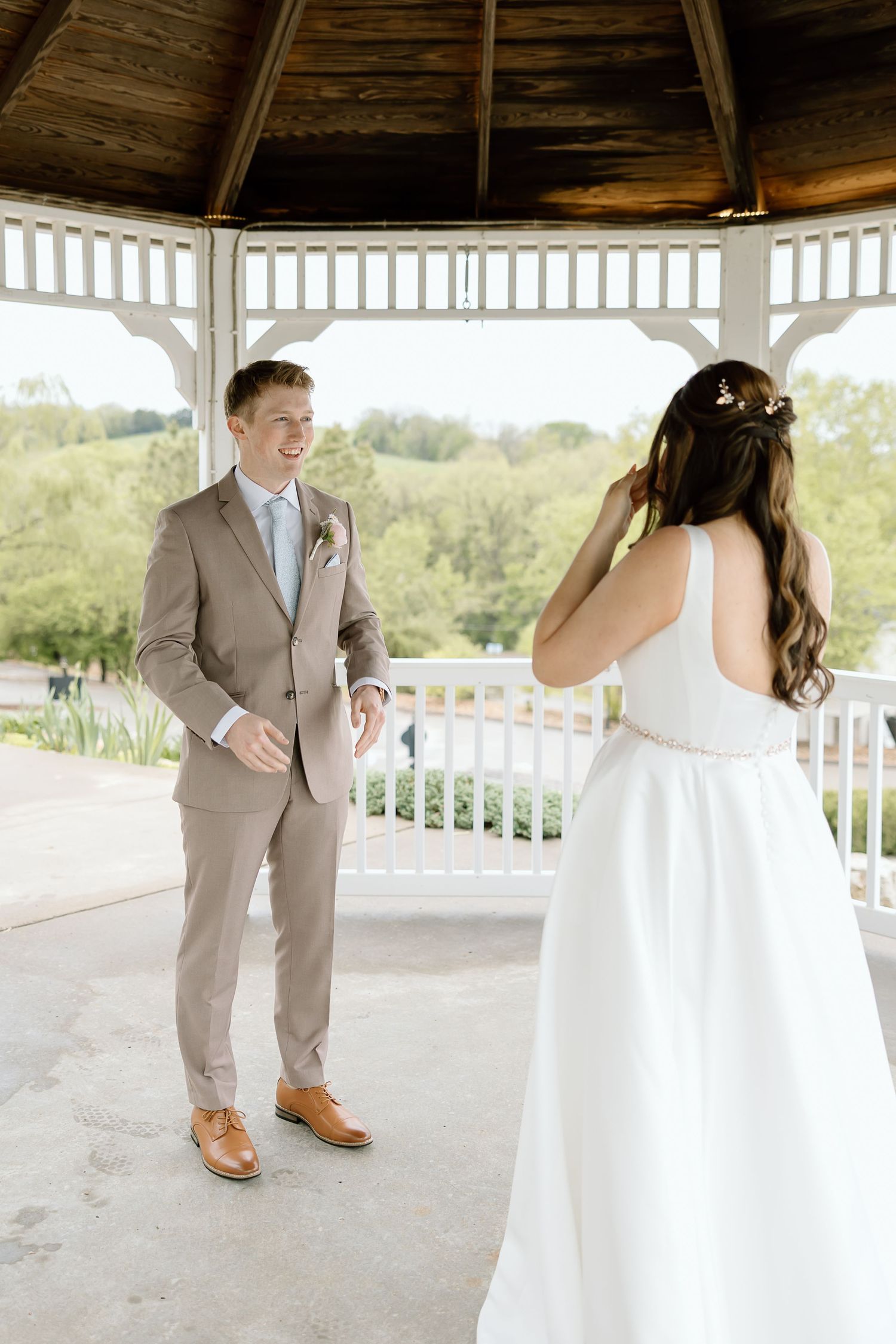 A couple shares their first dance under a white gazebo during their wedding celebration.