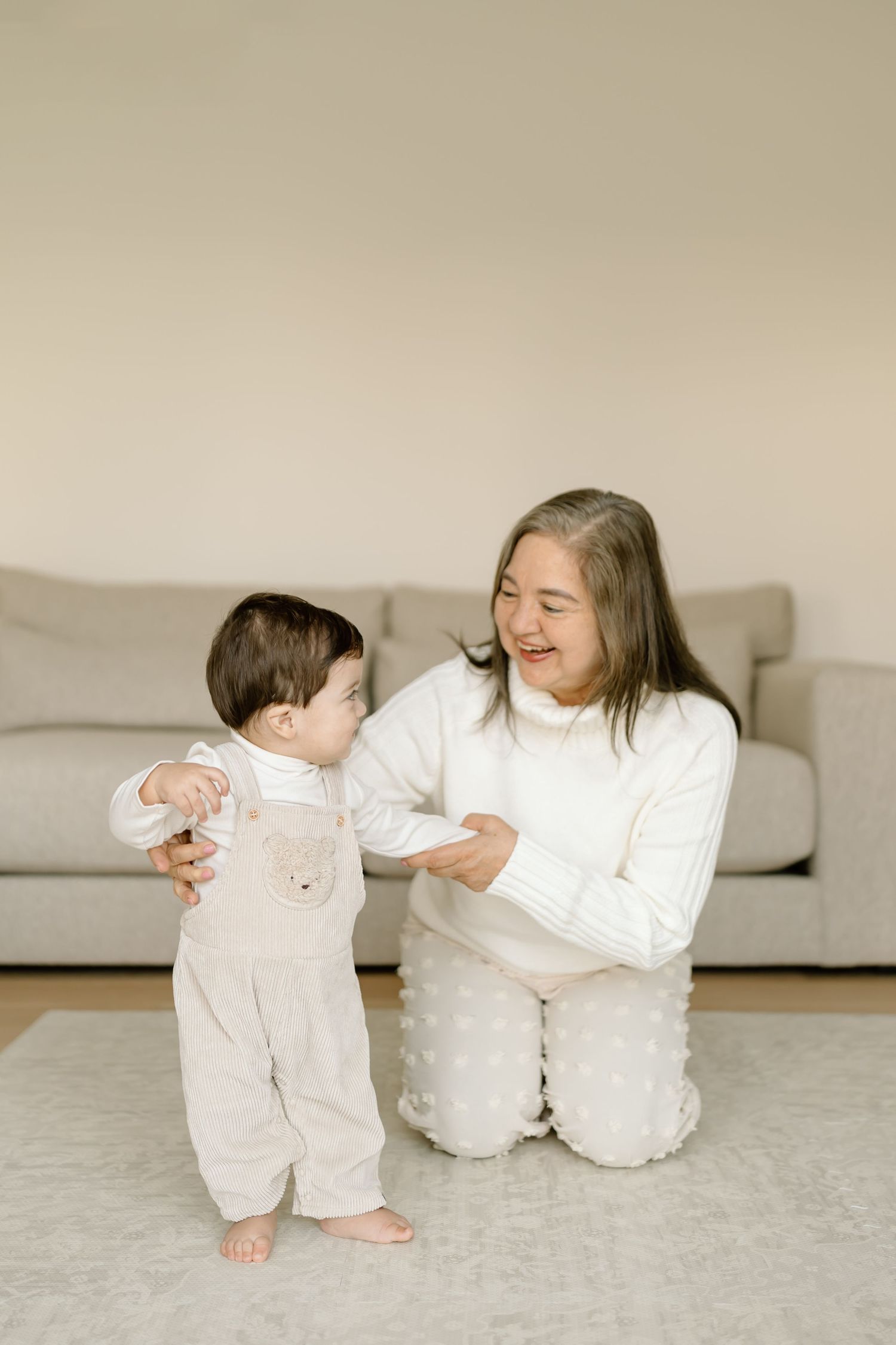 A heartwarming series of candid moments between a parent and baby in white outfits sitting on a light colored floor.