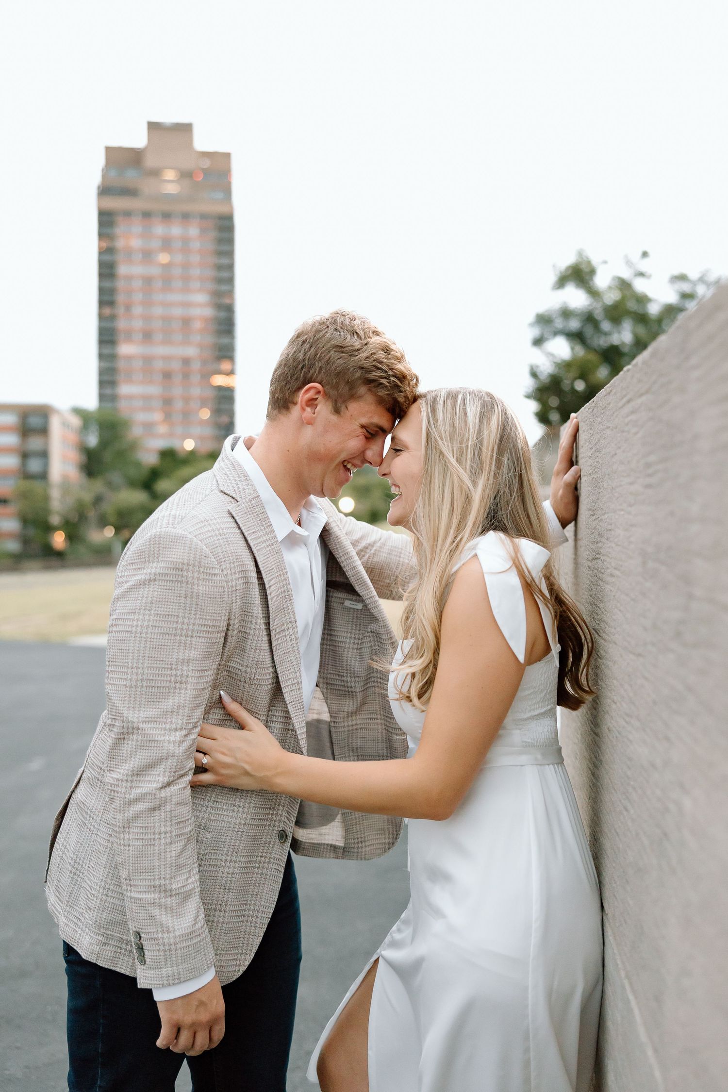 A couple in wedding attire shares intimate moments against a concrete wall in a series of romantic photos.