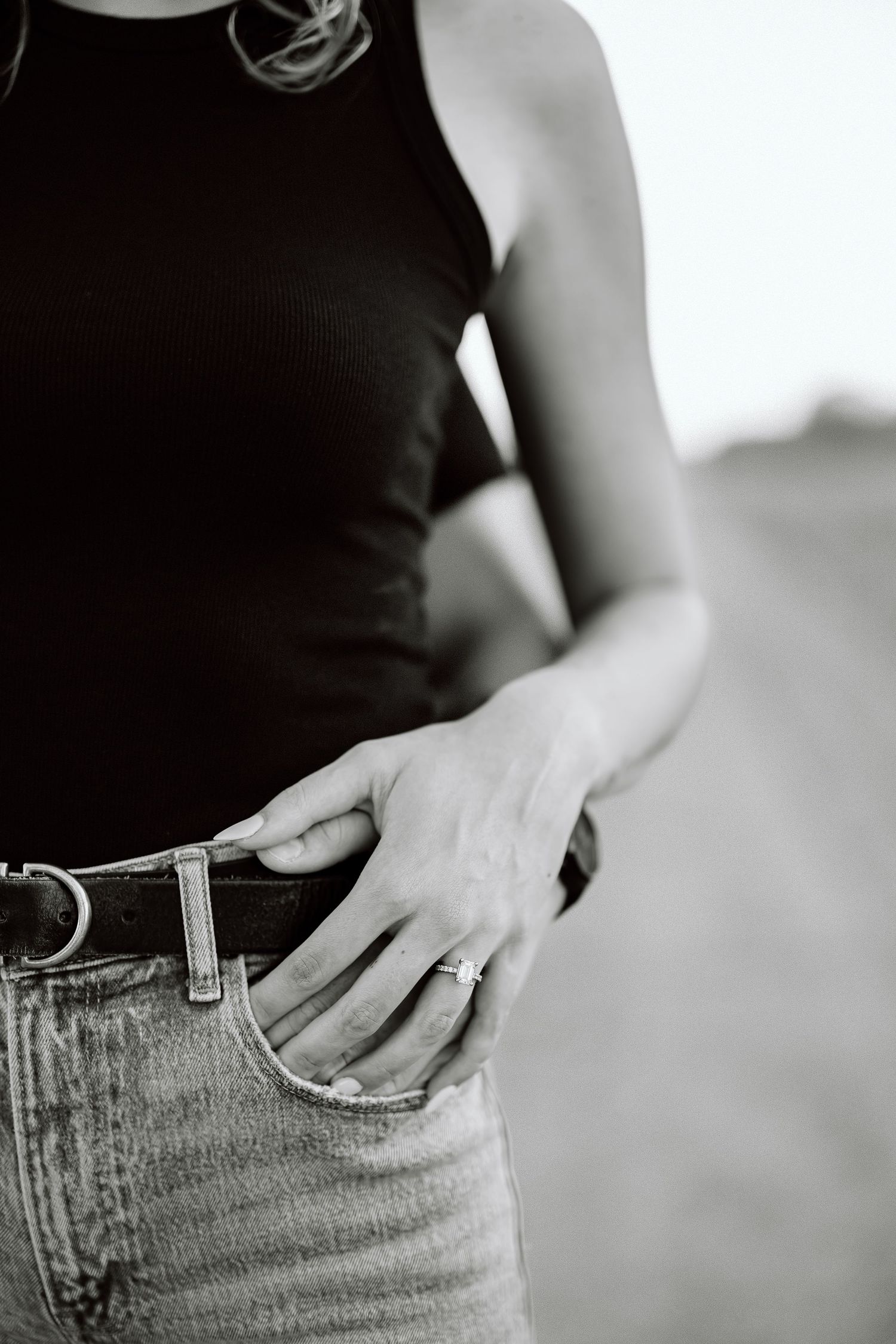 Close-up black and white photo of hands in jeans pockets showing casual fashion details.